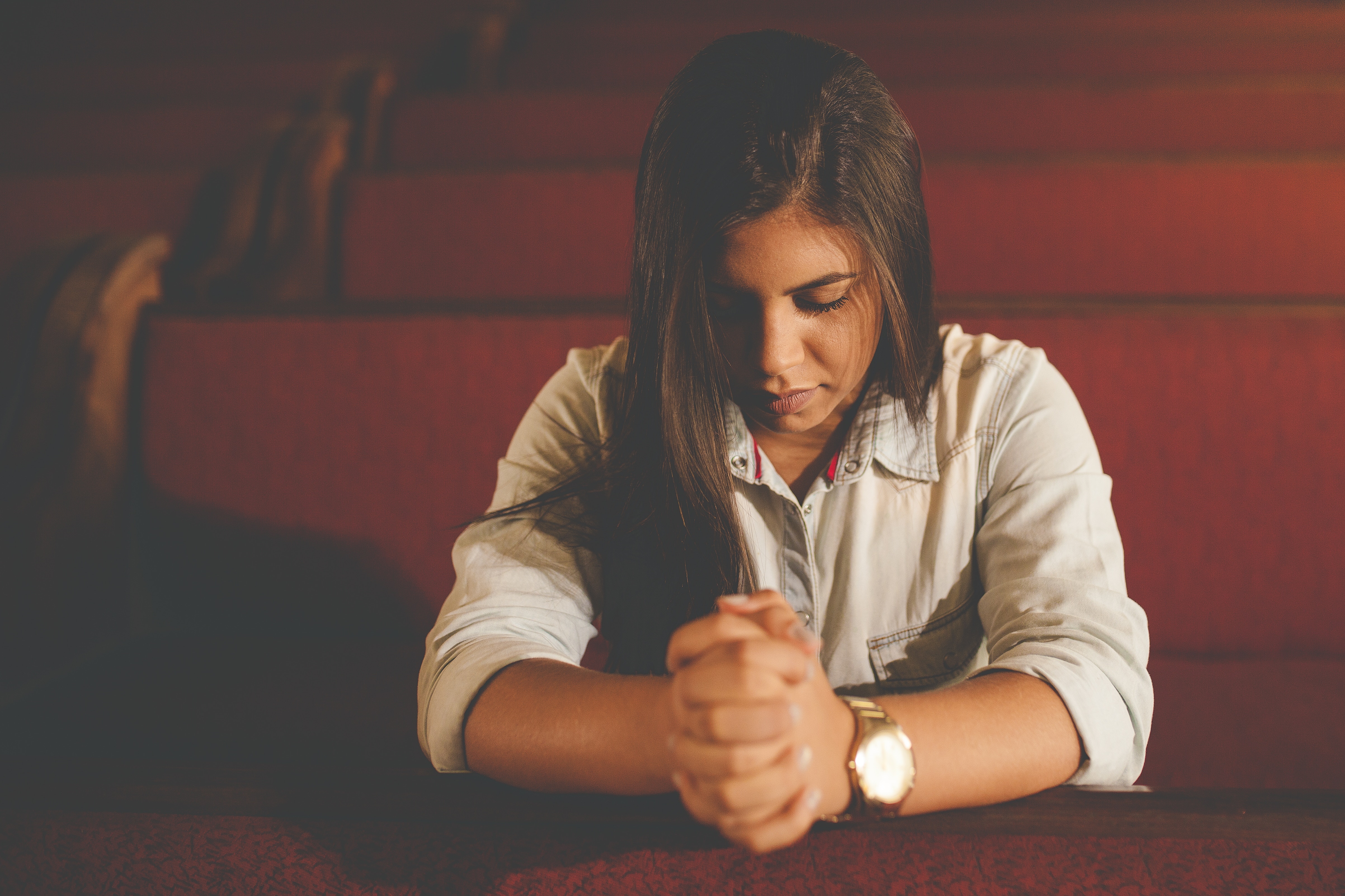 Woman praying in a church pew HD Wallpaper