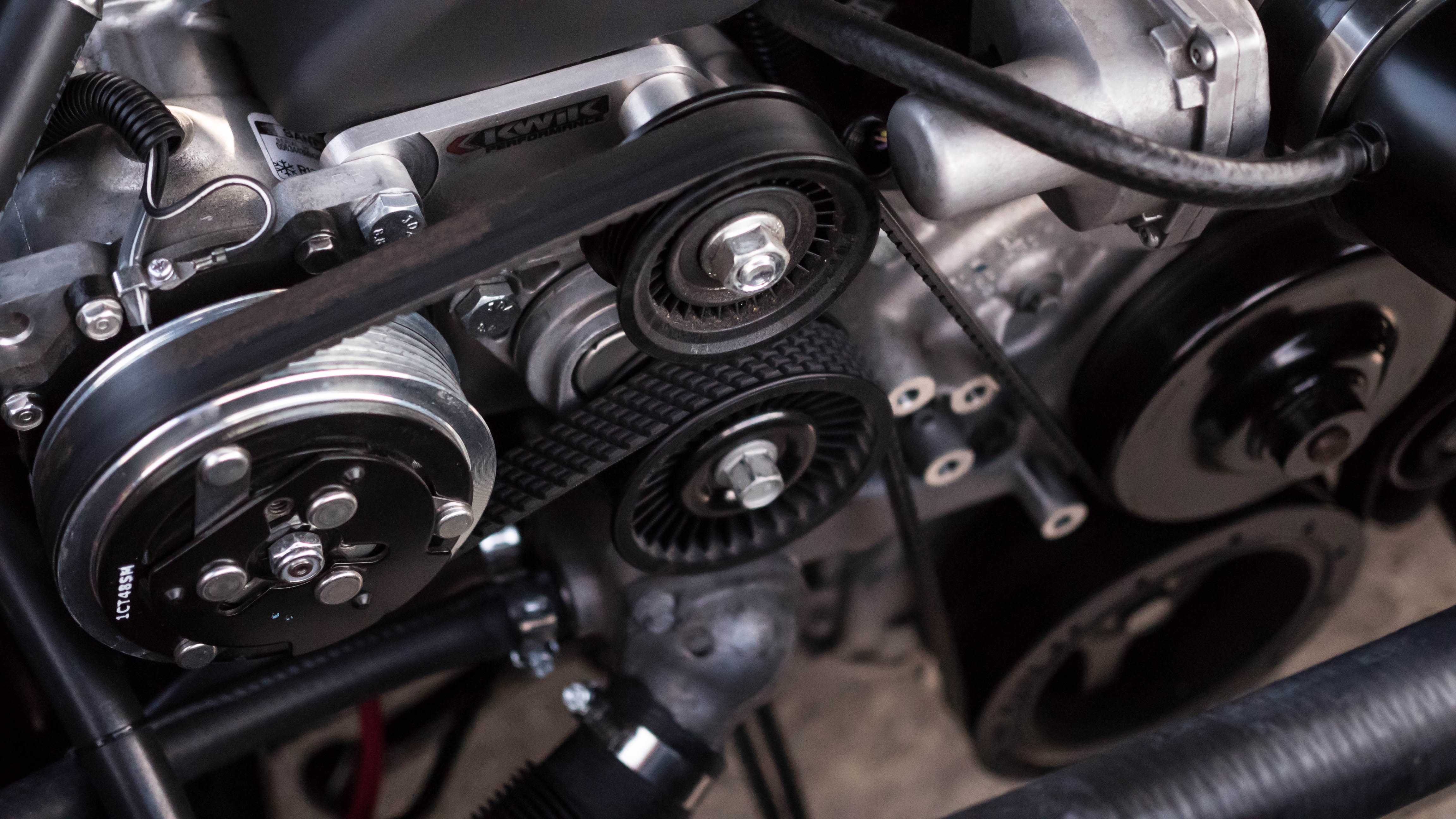 Close-up of a car engine with belts and pulleys HD Wallpaper