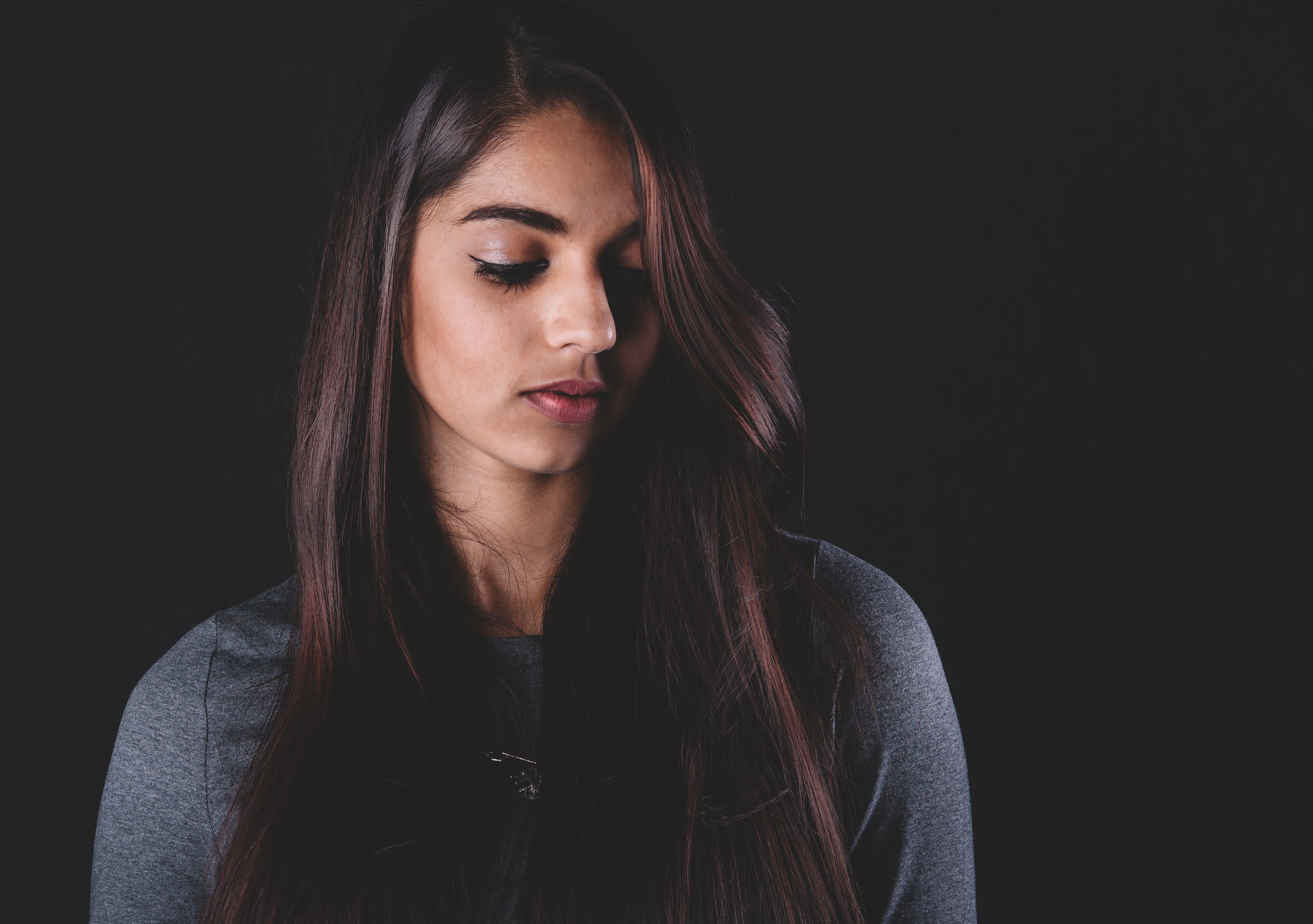 Woman with long dark hair looking down HD Wallpaper
