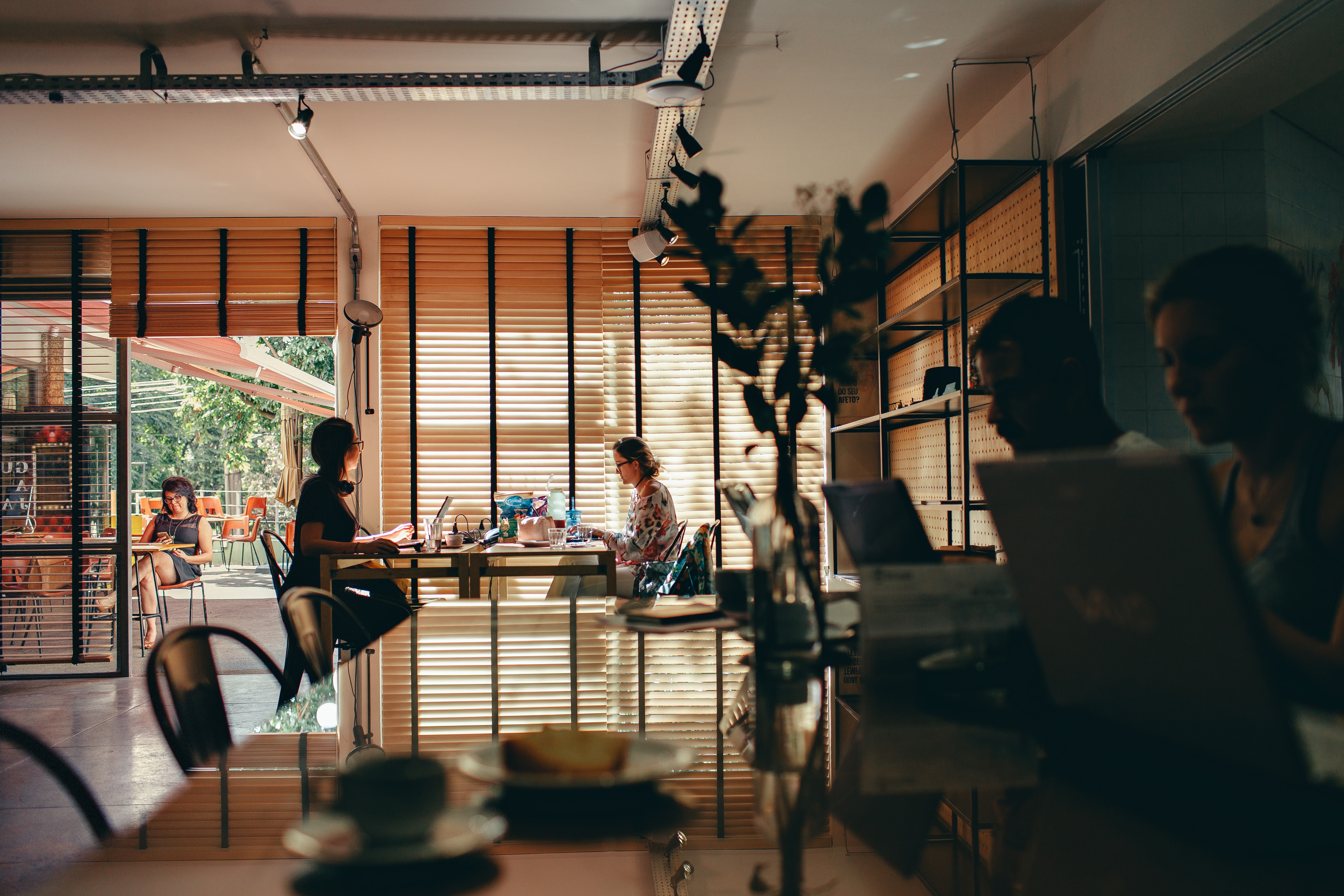 People working on laptops in a bright coffee shop HD Wallpaper