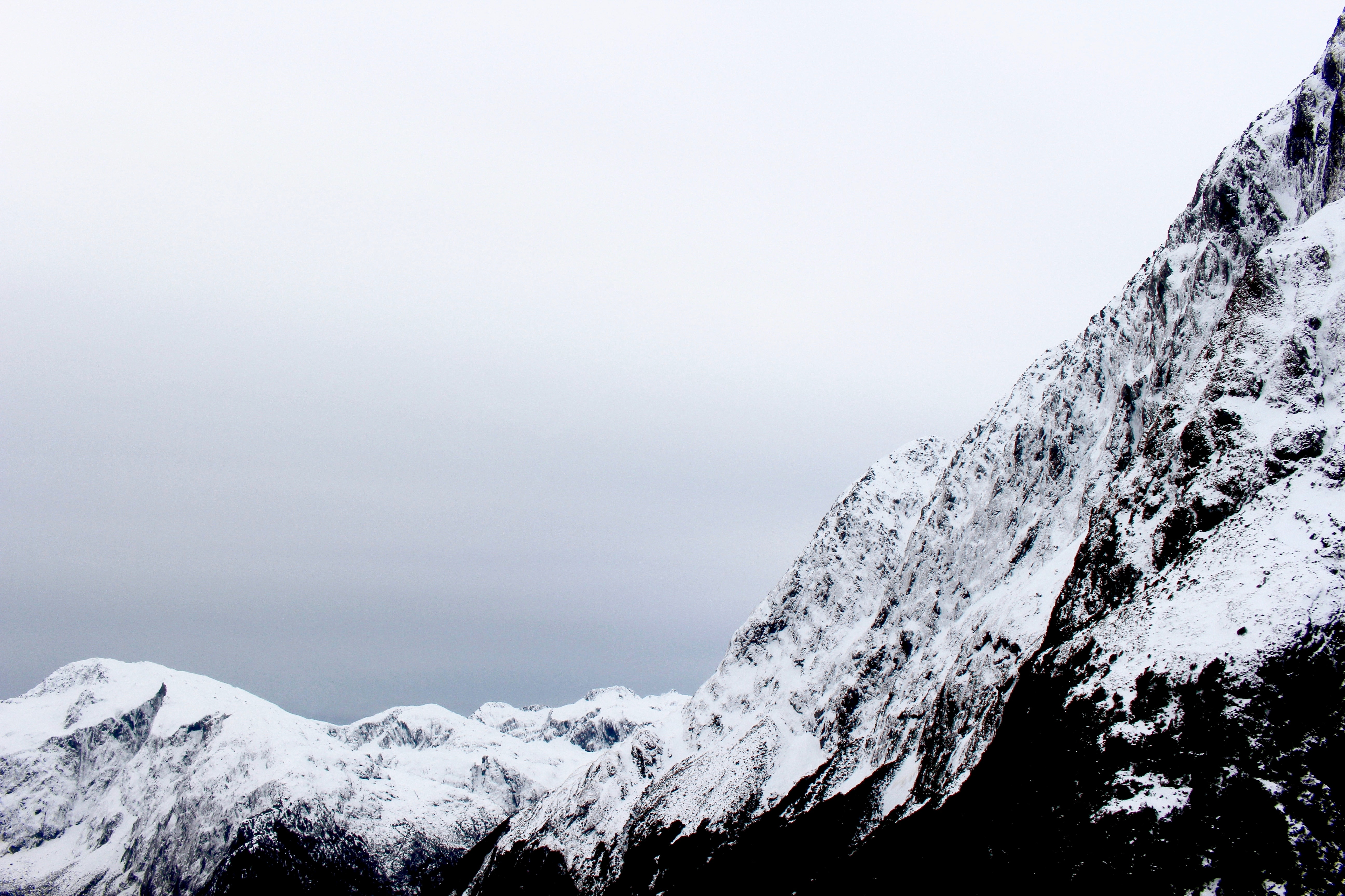 Snow-covered mountains in New Zealand under a cloudy sky HD Wallpaper