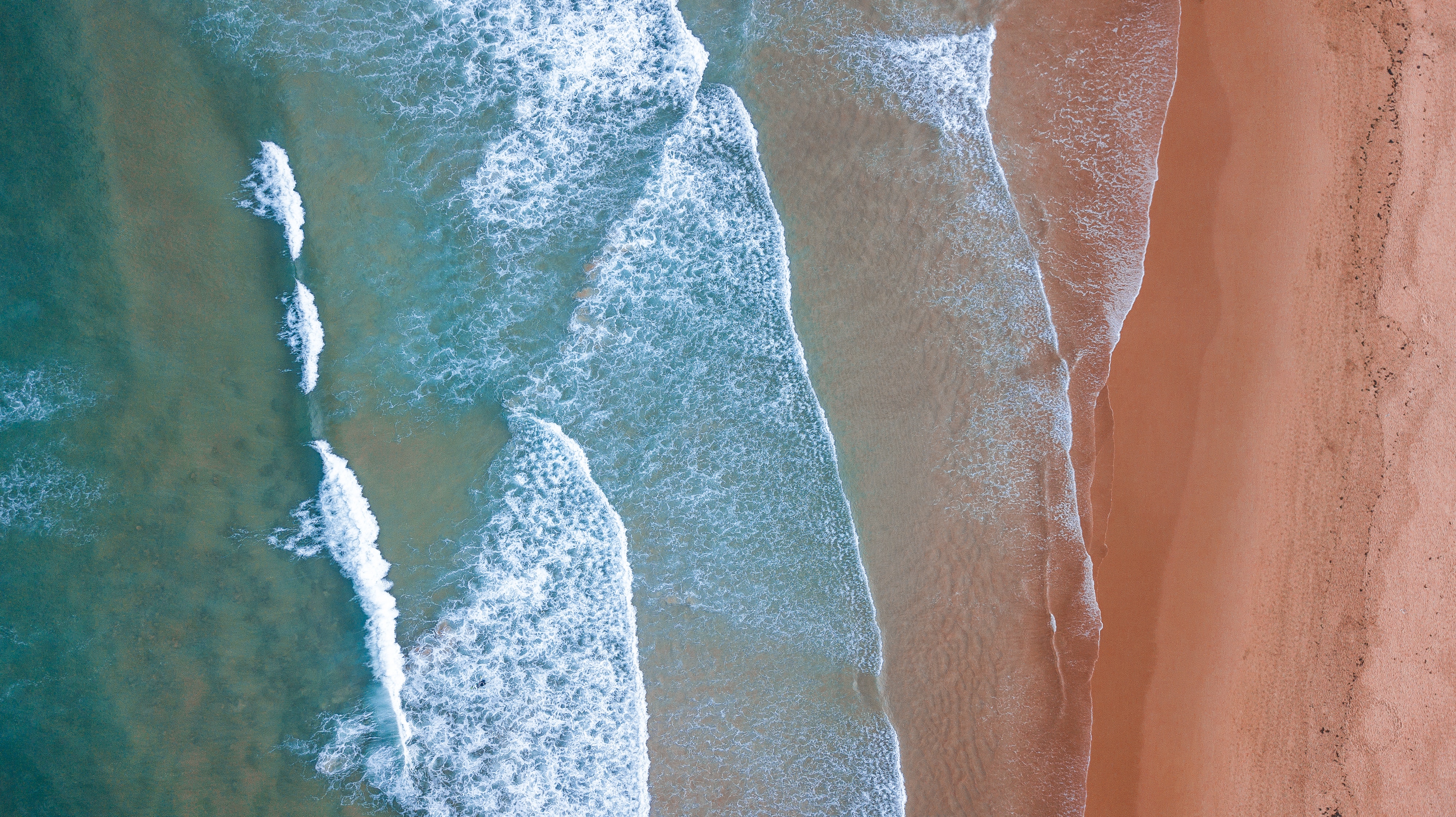 Aerial view of waves crashing on a sandy shore HD Wallpaper