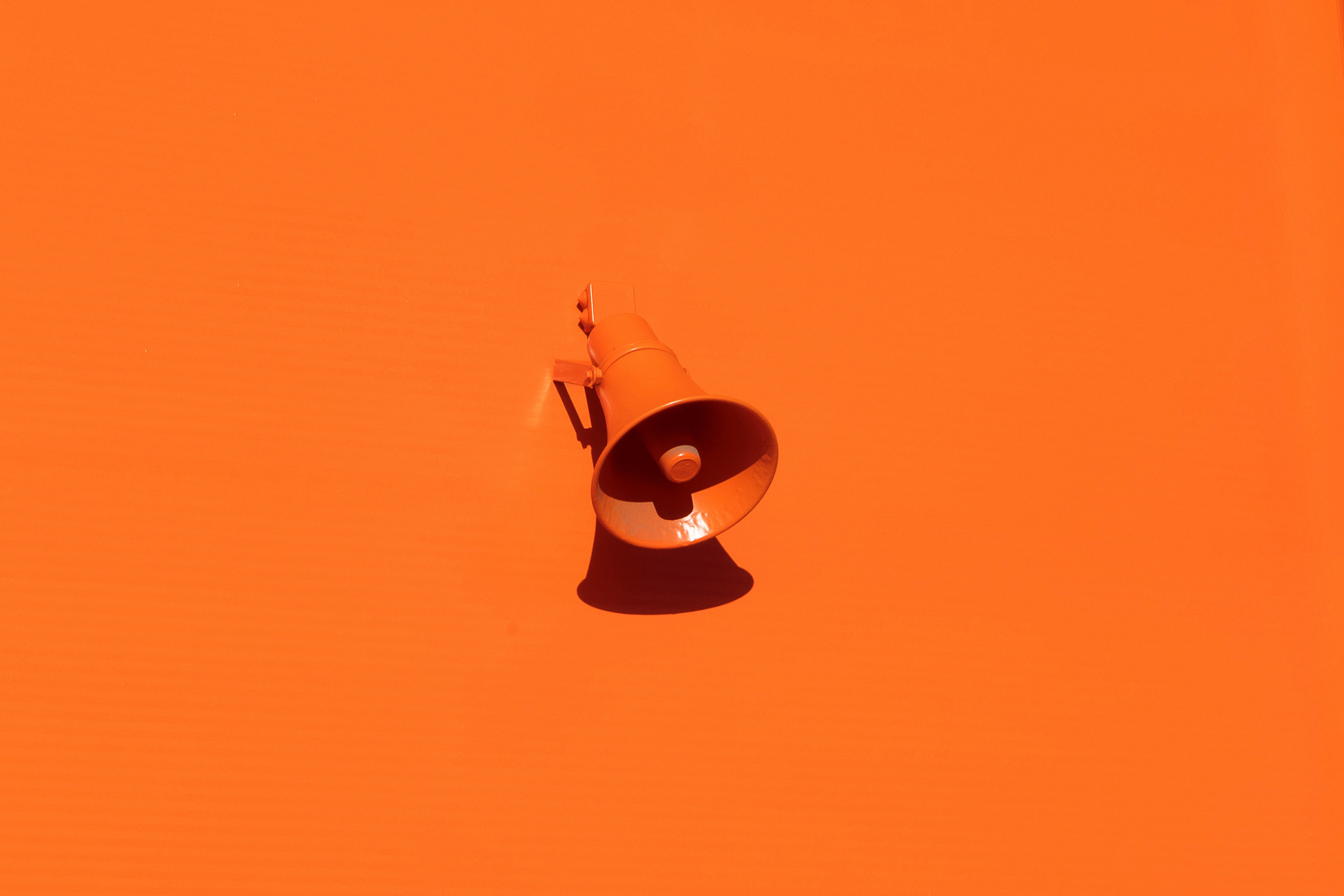 Orange megaphone mounted on an orange wall HD Wallpaper