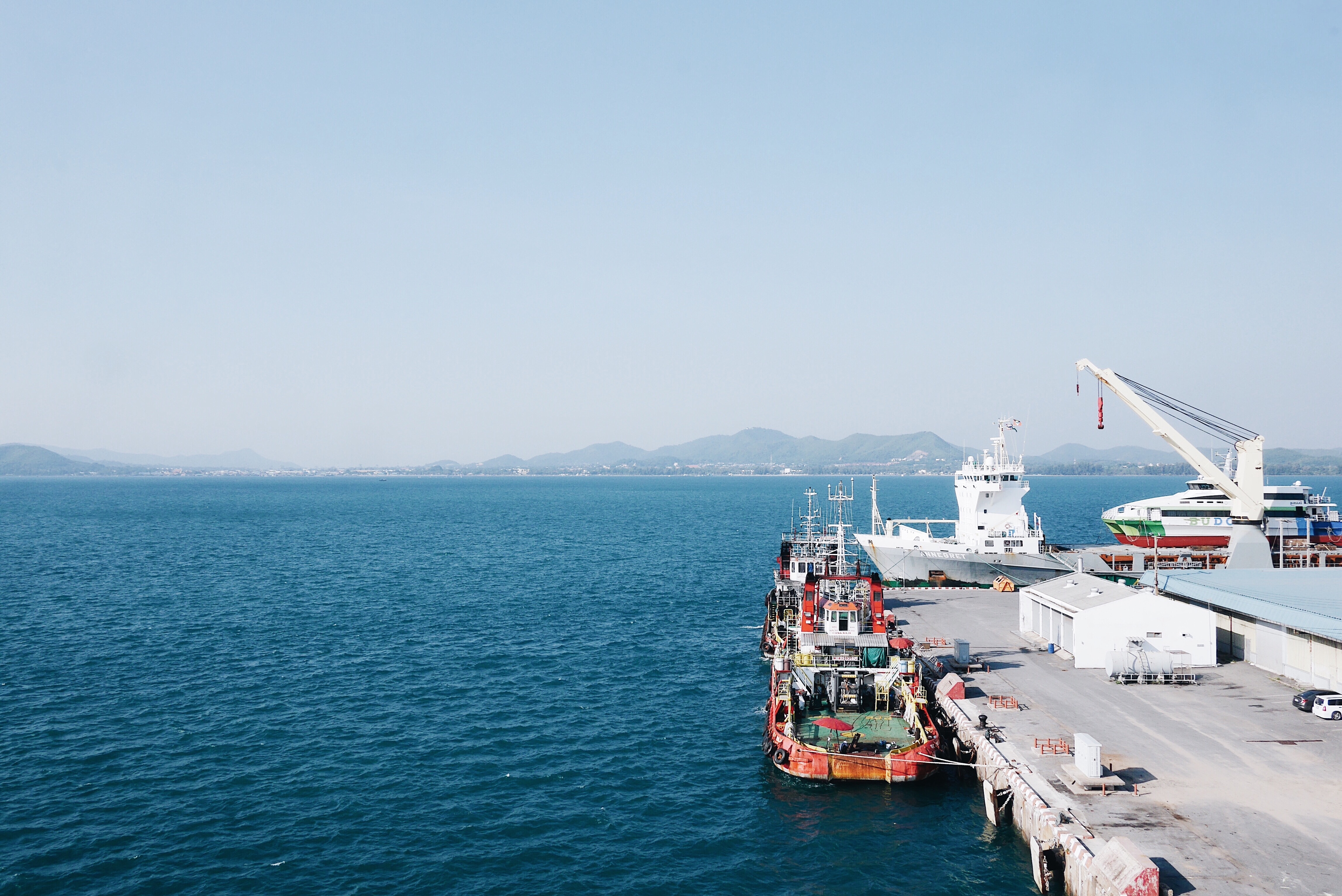 Boats docked at a harbor with mountains in the background HD Wallpaper