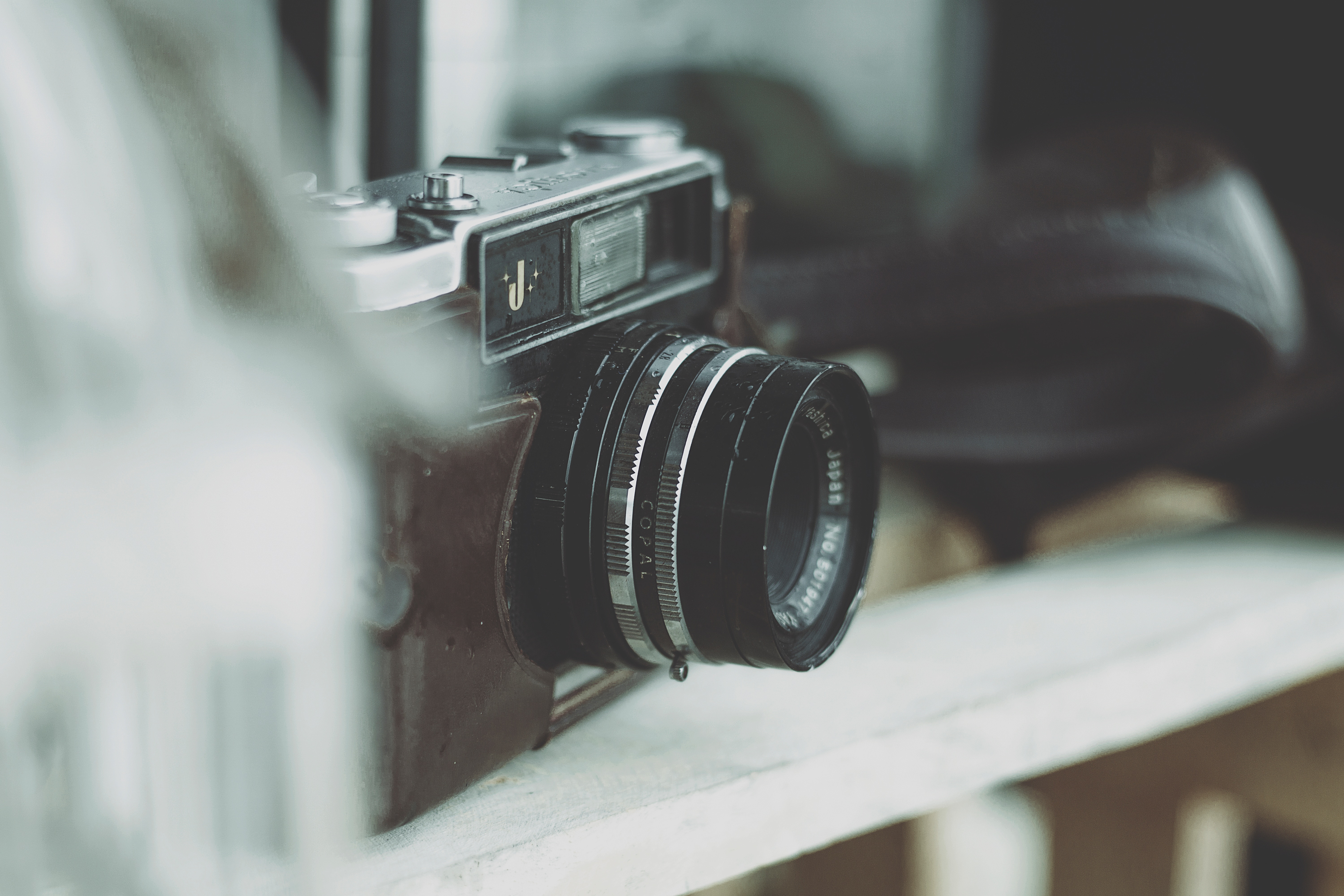Vintage film camera with lens on a shelf HD Wallpaper