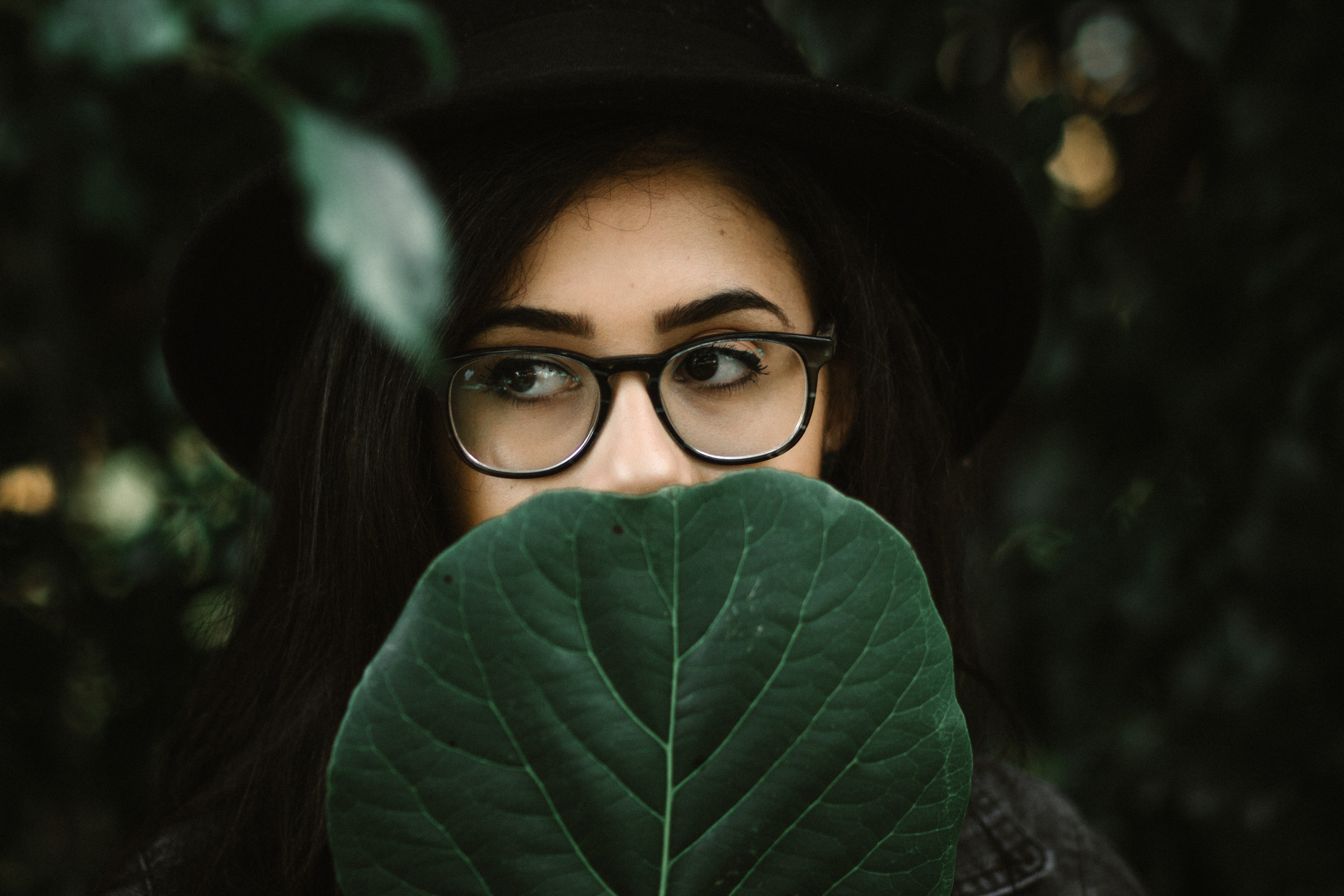 Woman wearing glasses and hat holding a leaf HD Wallpaper