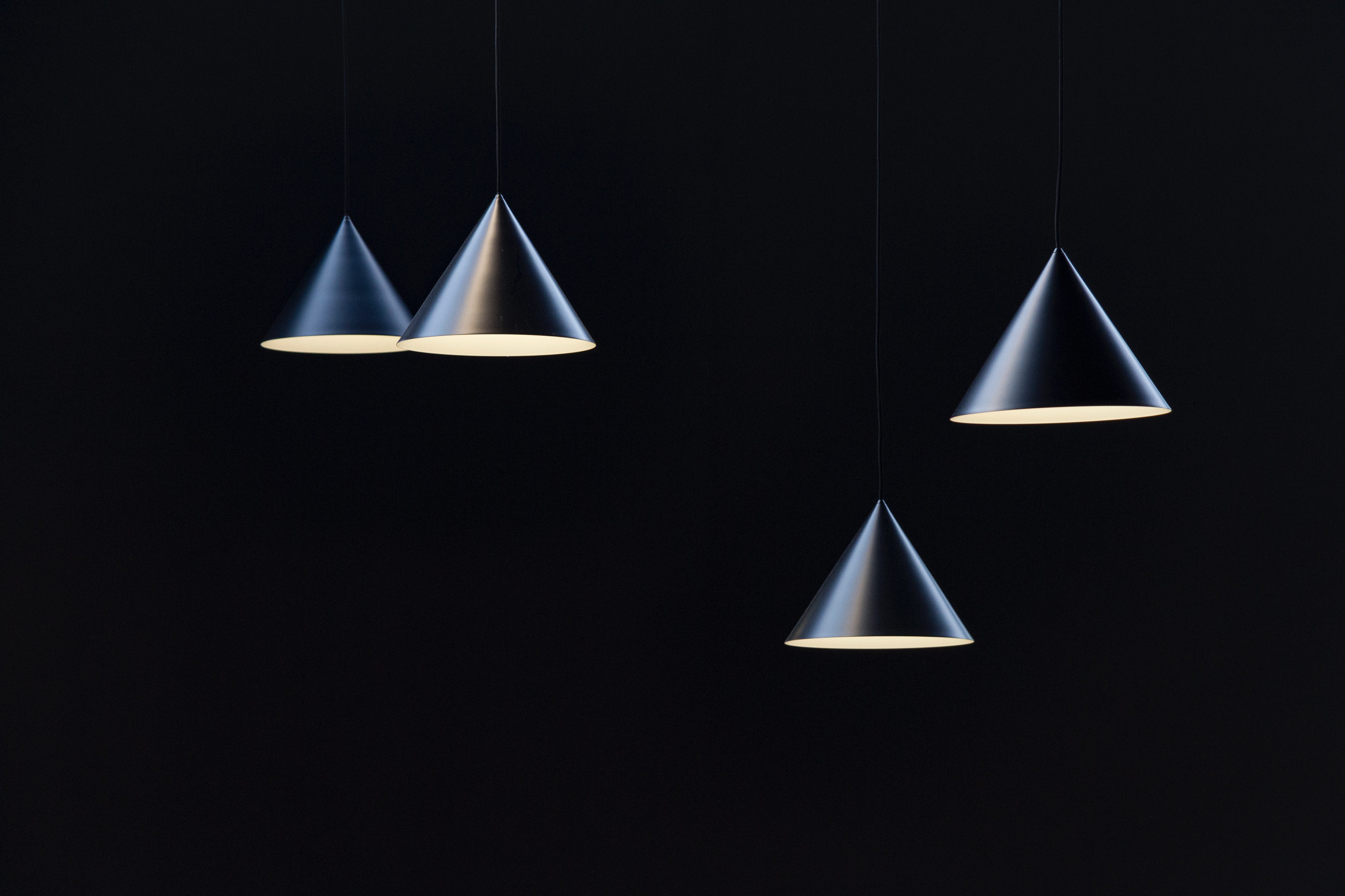 Four black cone-shaped pendant lights against a dark background HD Wallpaper