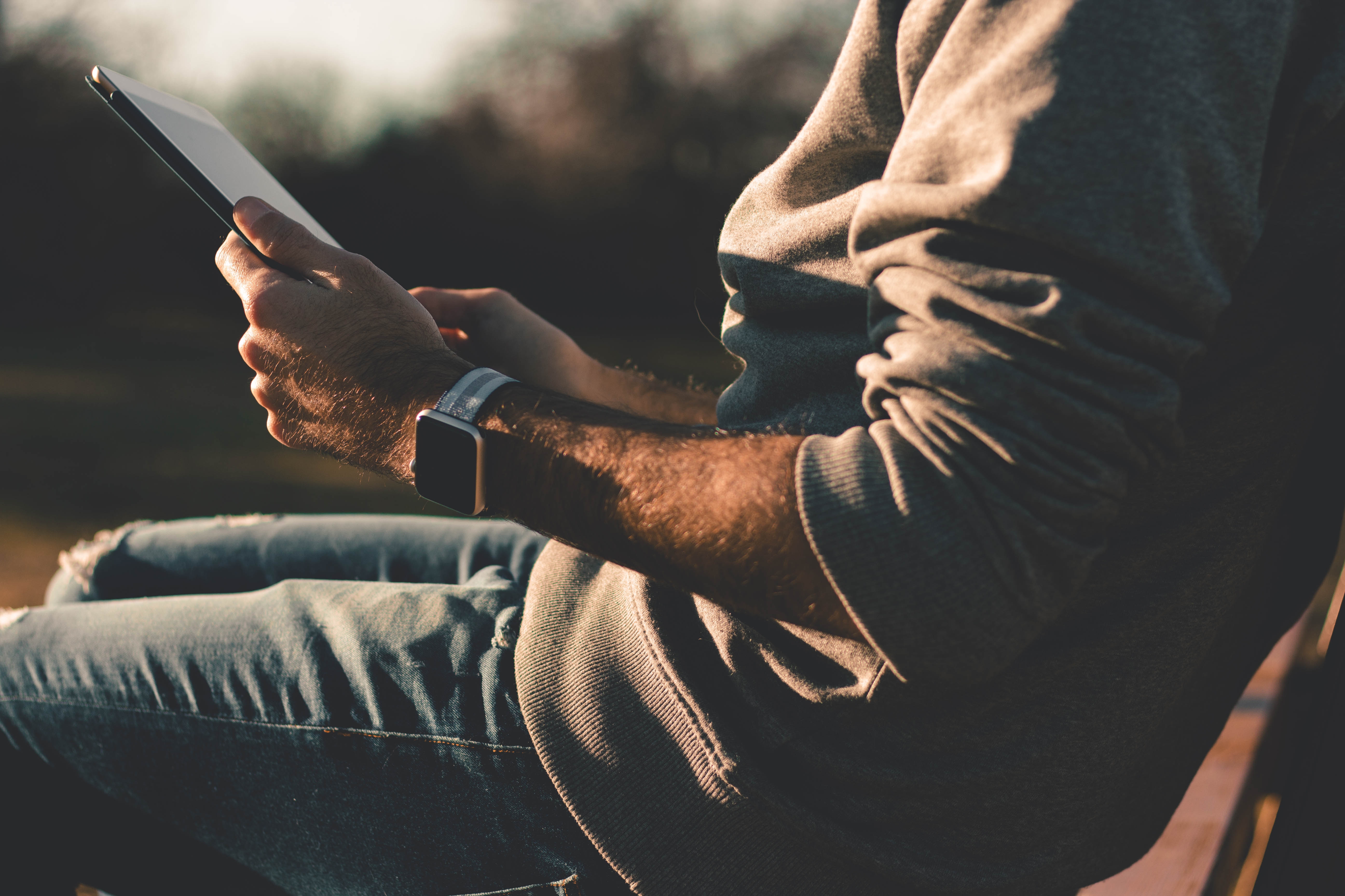 Man with Apple Watch and iPad Pro outdoors at sunset HD Wallpaper