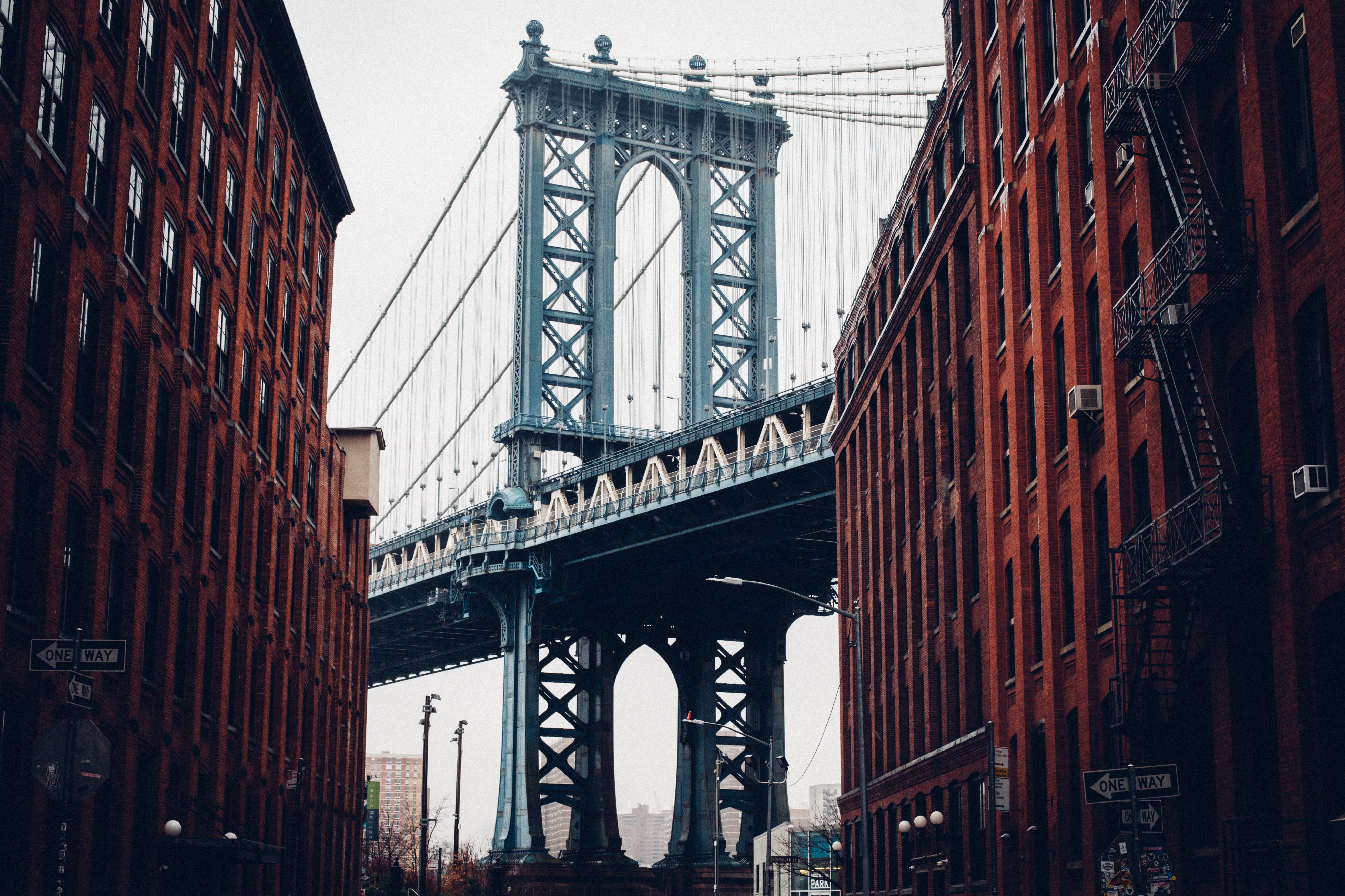Manhattan Bridge between brick buildings in New York City HD Wallpaper