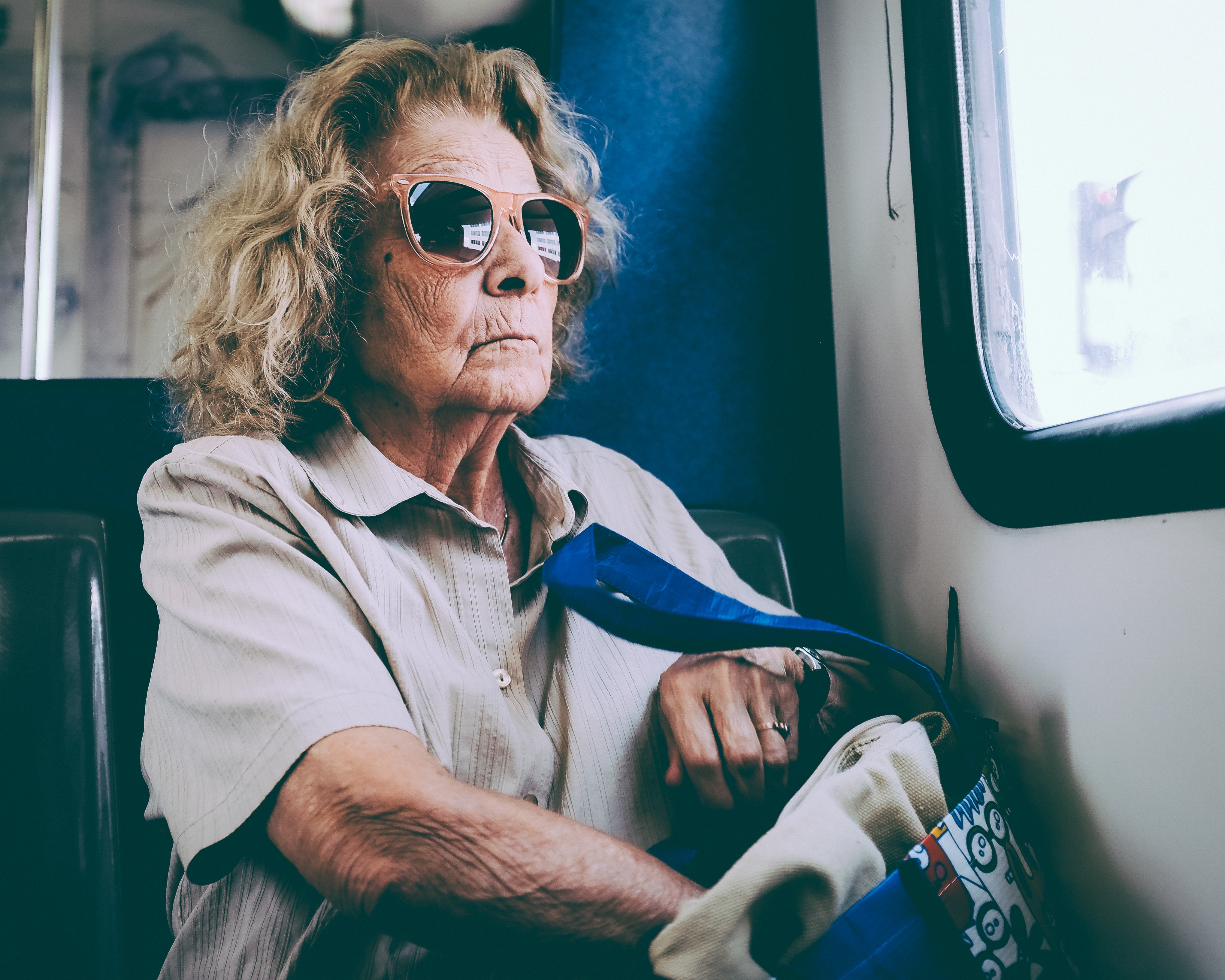 Elderly woman with sunglasses on a train HD Wallpaper