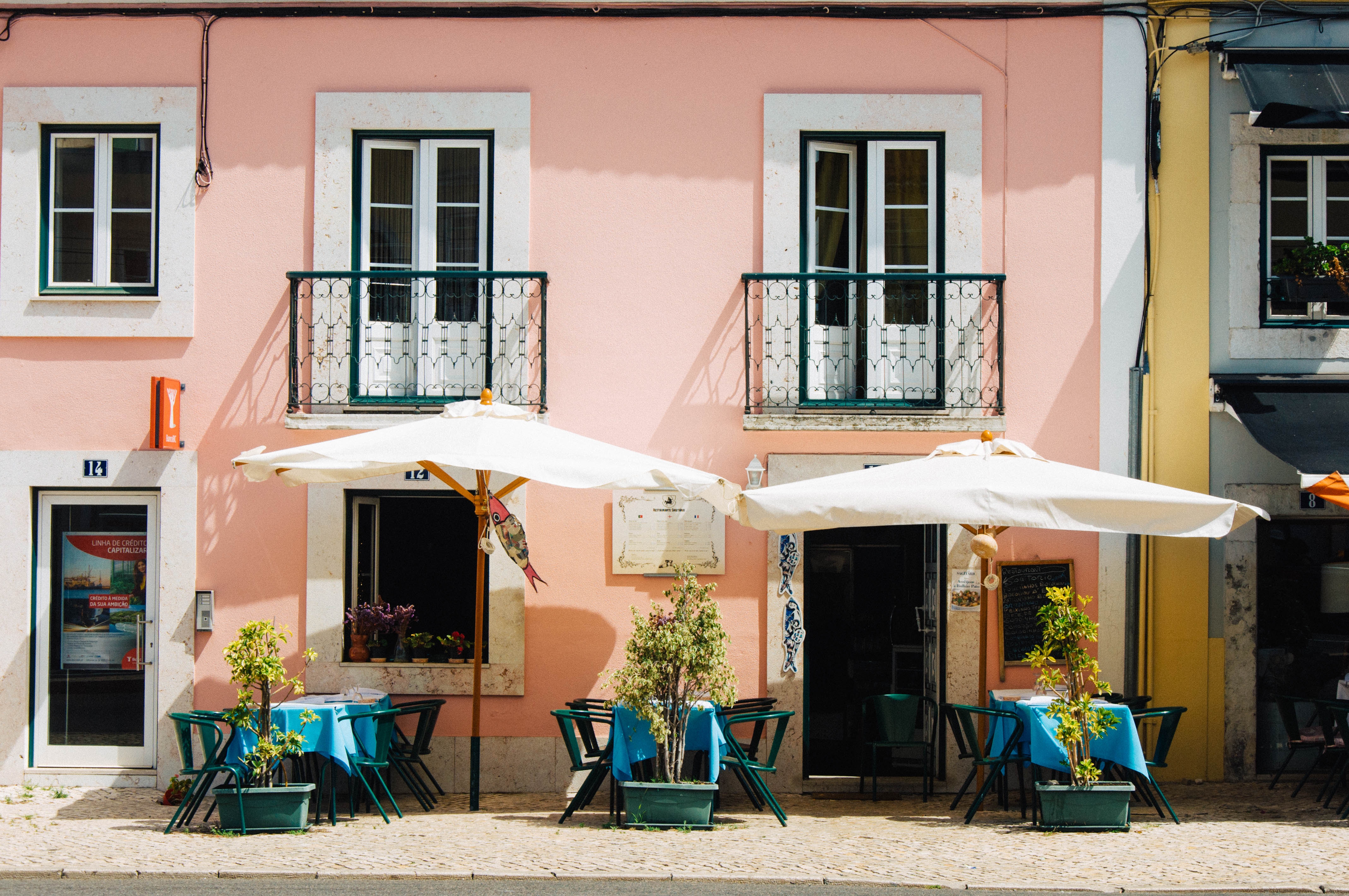 Pink building with outdoor cafe seating in Lisbon HD Wallpaper