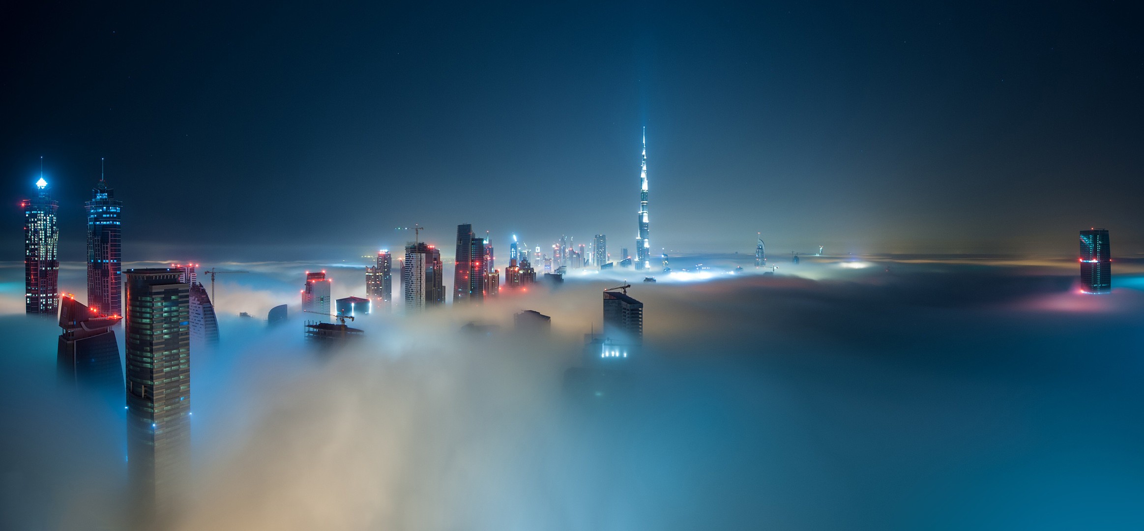 Dubai skyline shrouded in mist at night with Burj Khalifa HD Wallpaper