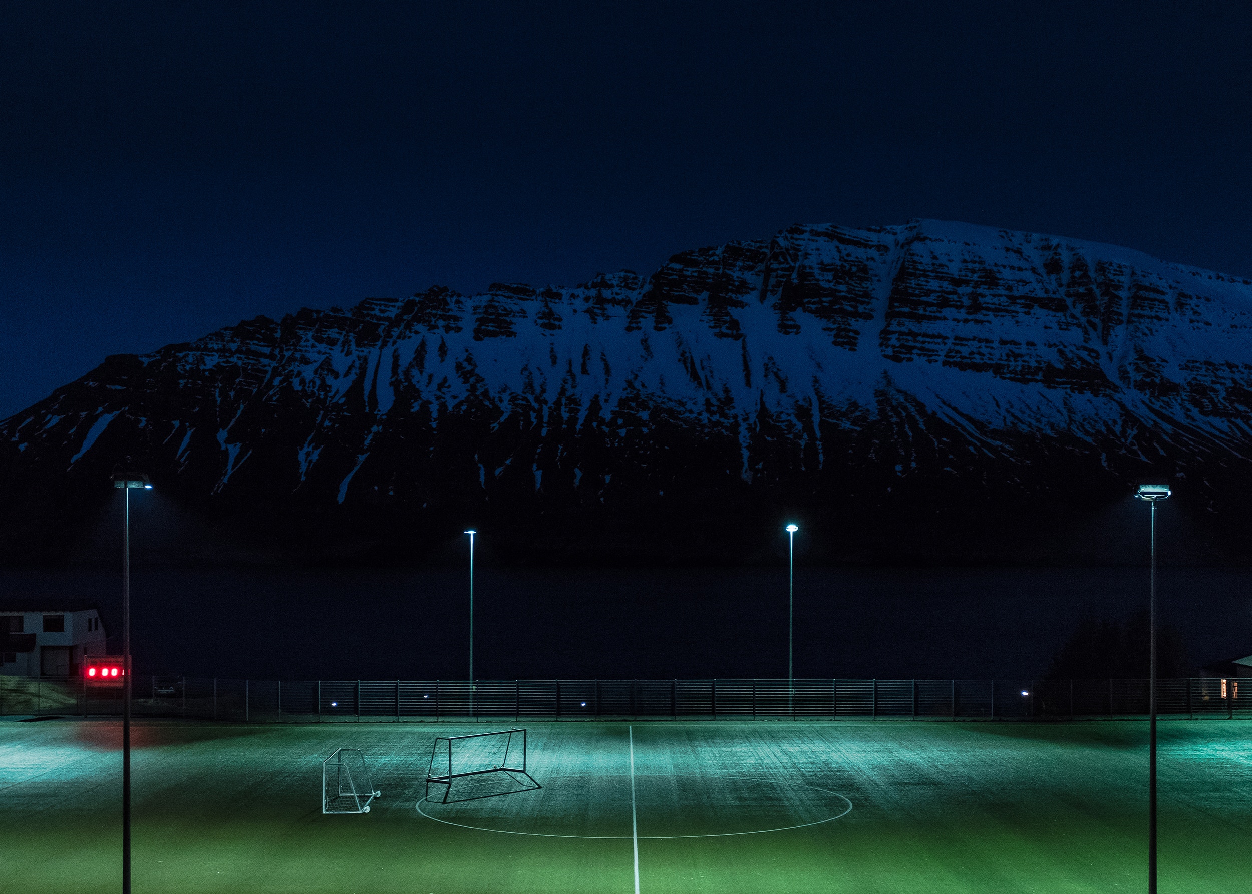 Soccer field at night with snowy mountain in Iceland HD Wallpaper