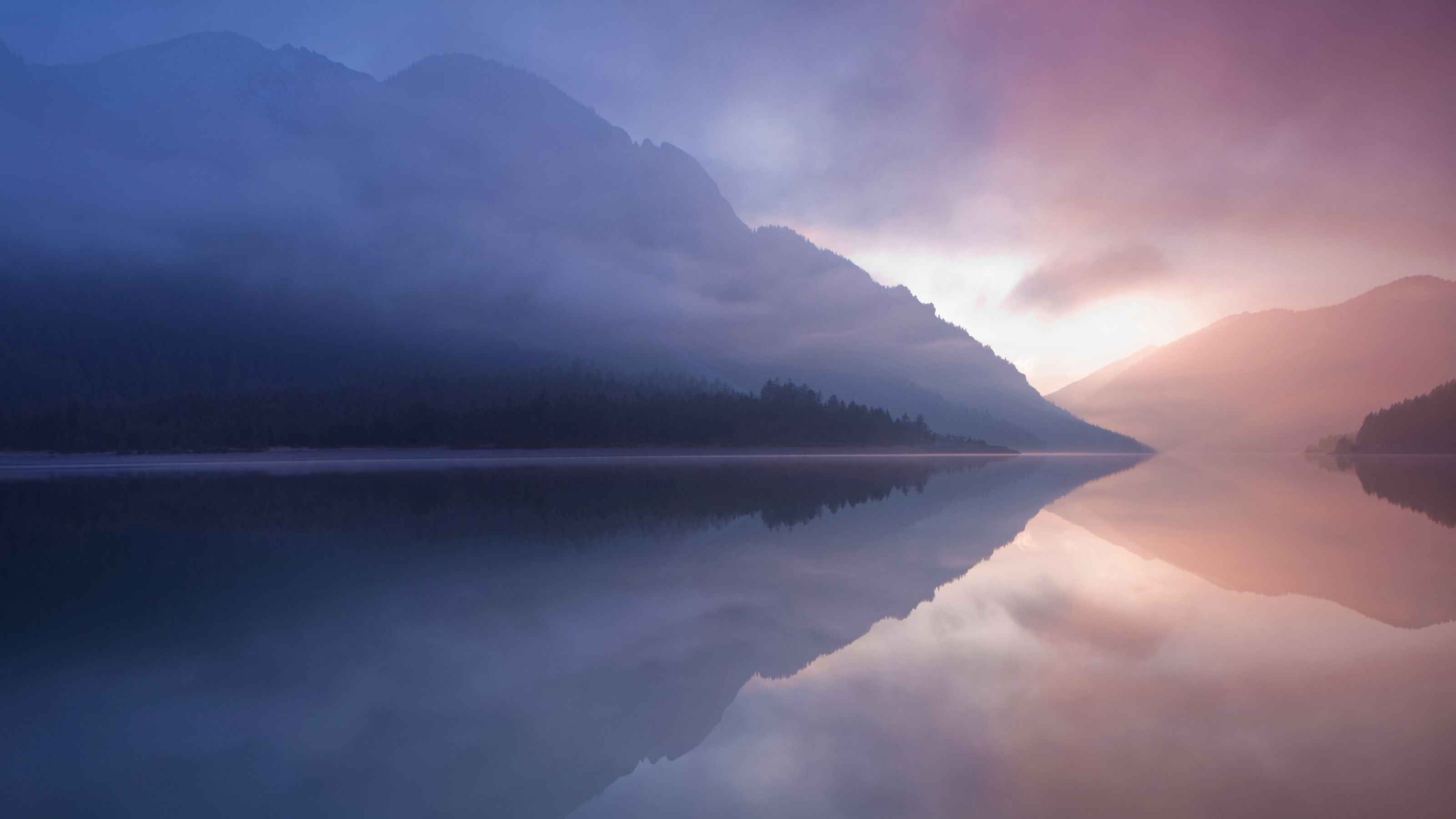 Misty mountains reflected in a calm lake at sunrise HD Wallpaper