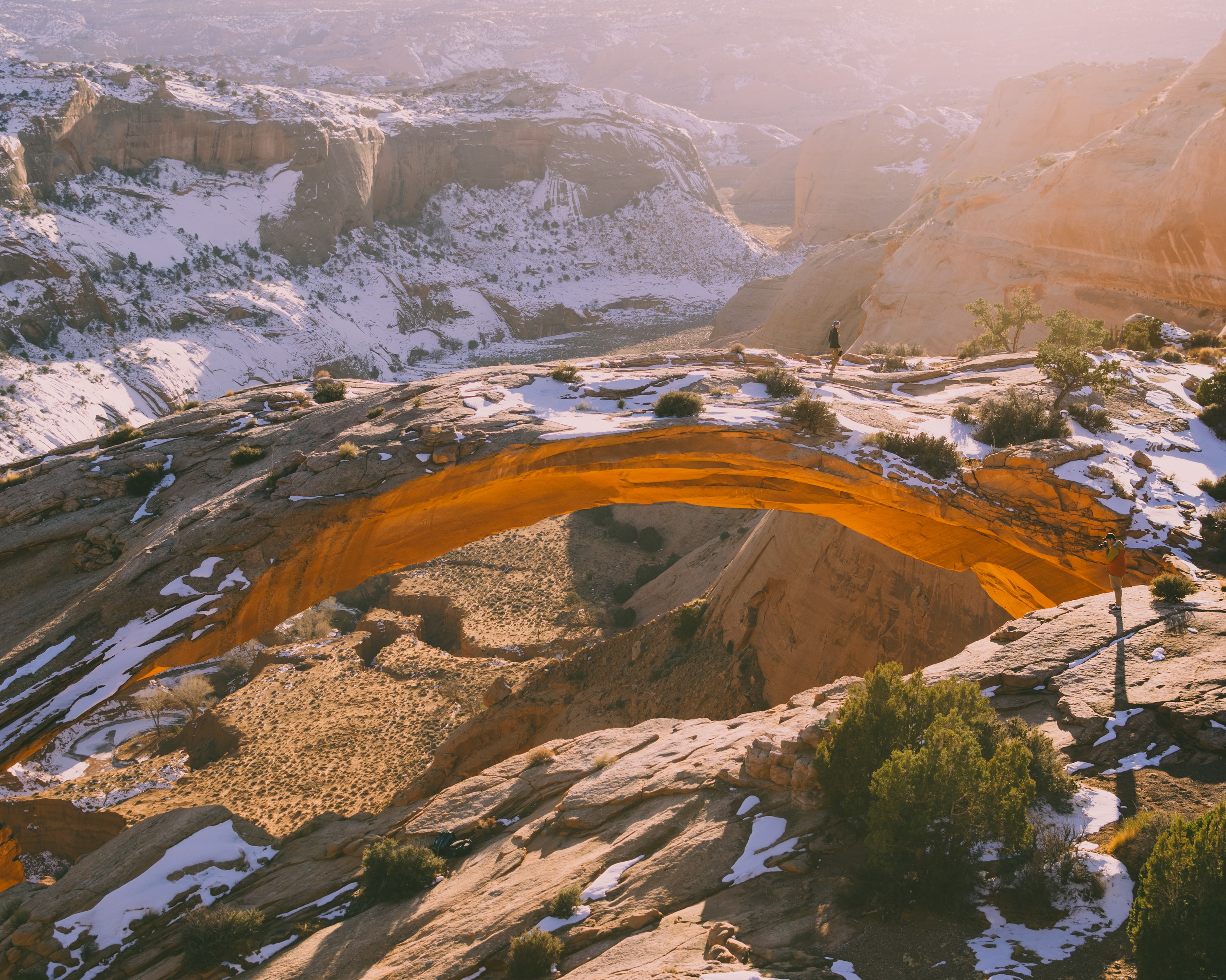 Person standing on a snowy arch in a canyon HD Wallpaper