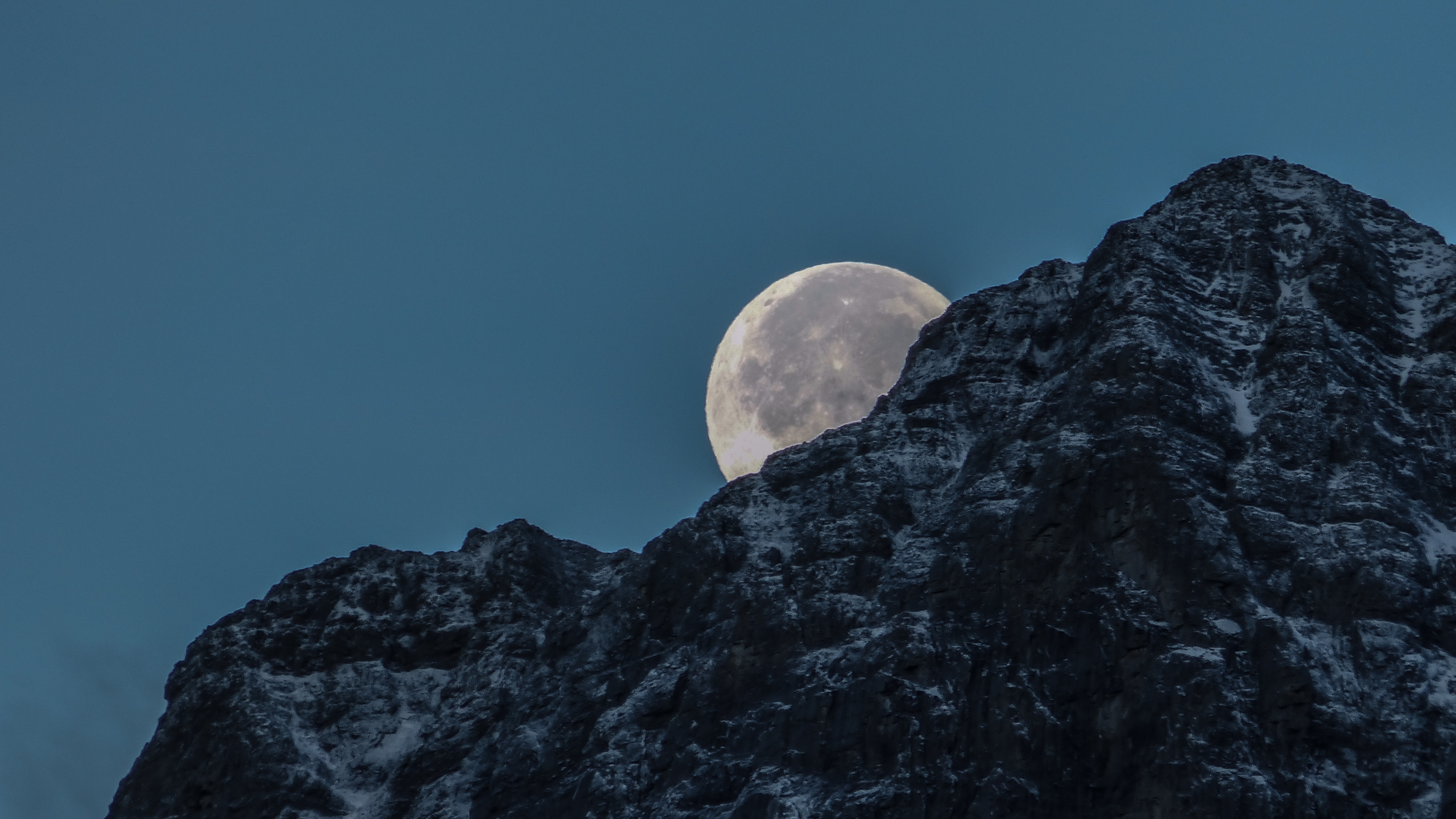Full moon rising behind a snow-capped mountain HD Wallpaper