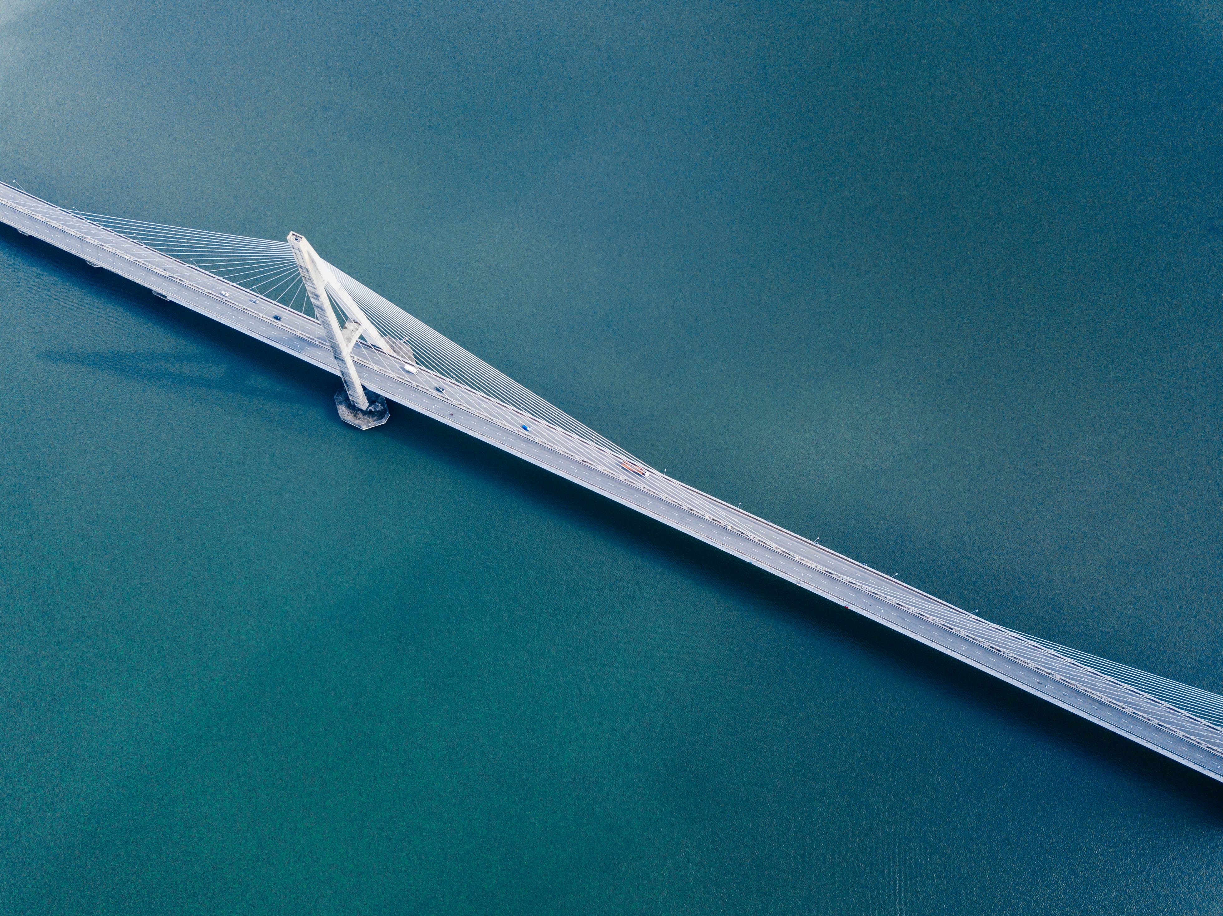 Aerial view of a cable-stayed bridge over blue water HD Wallpaper