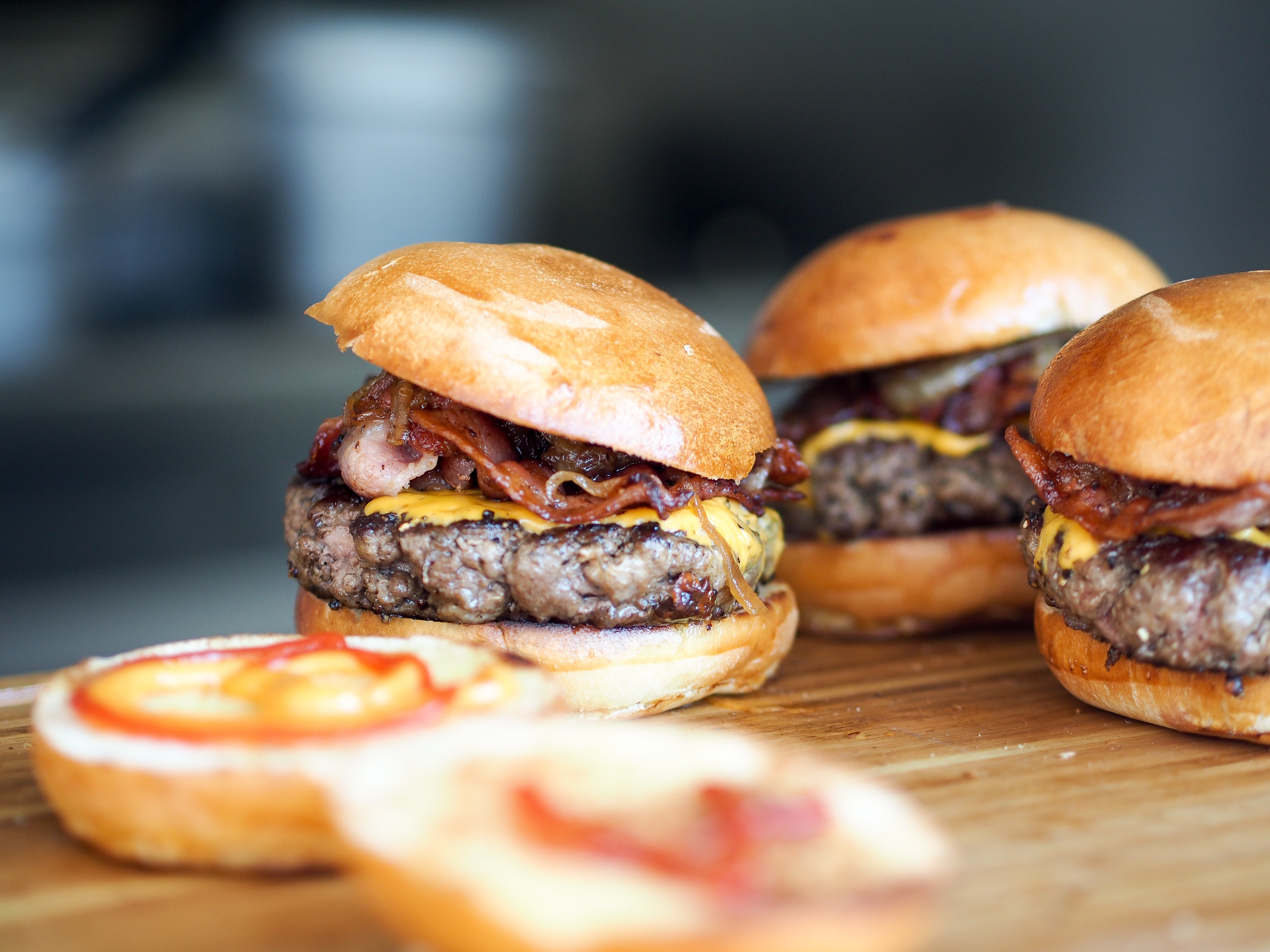 Four bacon cheeseburgers on a wooden board HD Wallpaper
