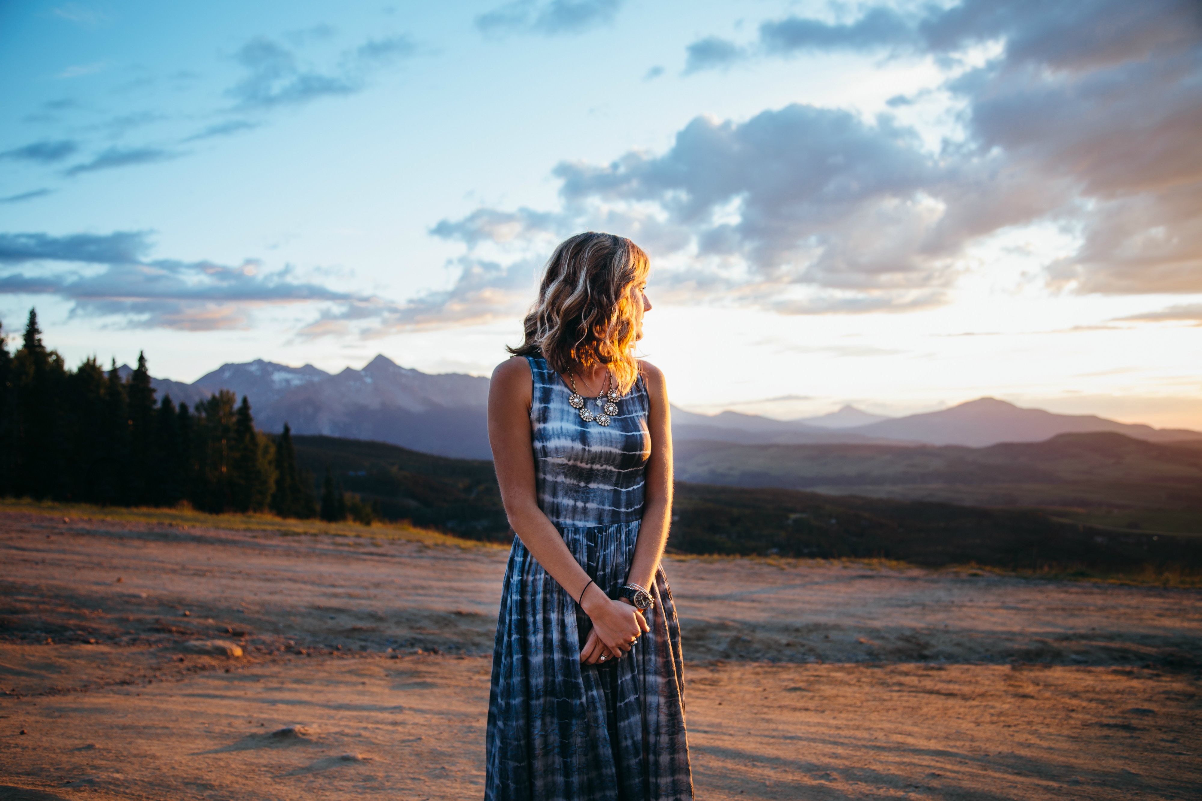 Woman in a tie-dye dress at sunset with mountains HD Wallpaper