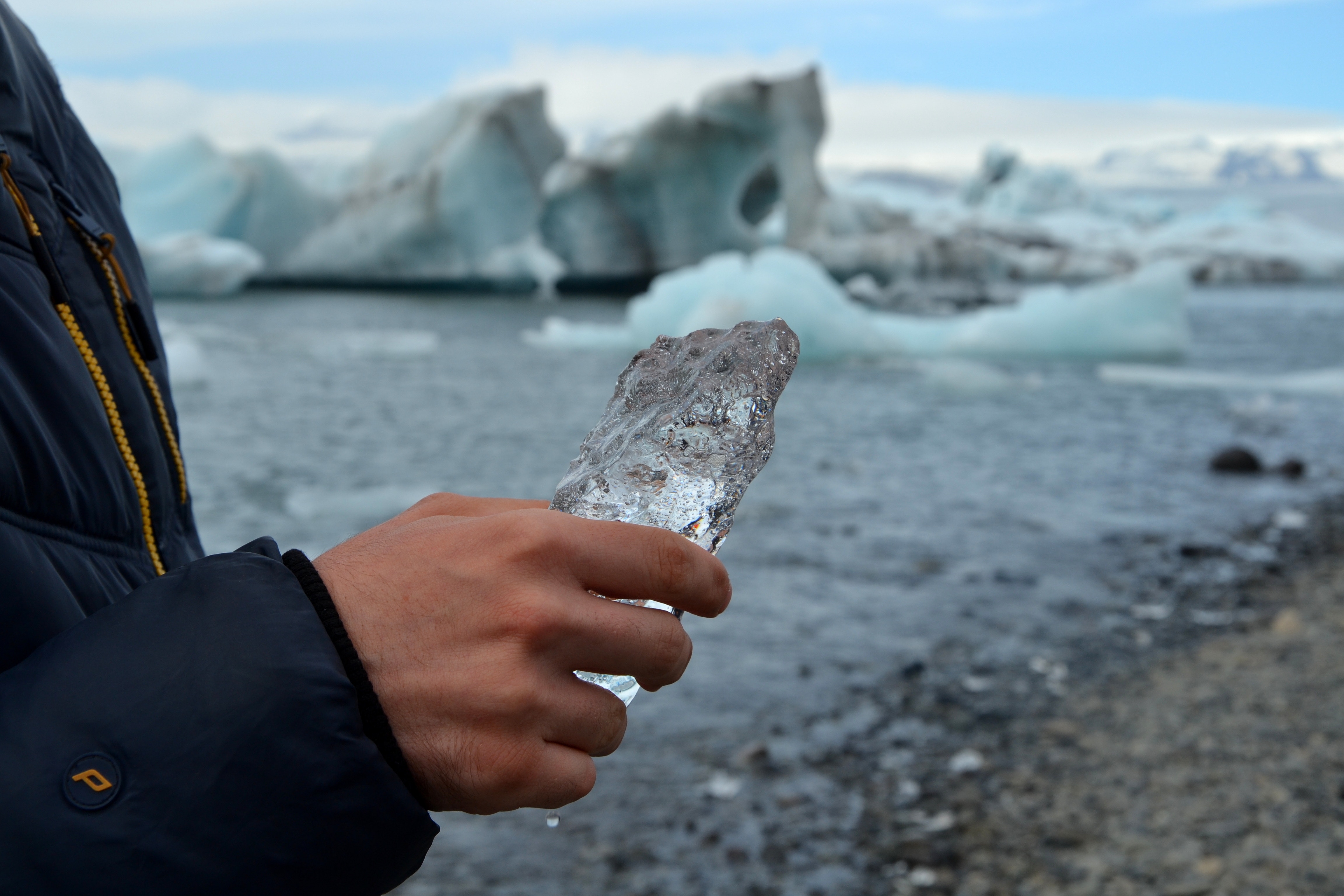 Person holding ice in front of glaciers HD Wallpaper