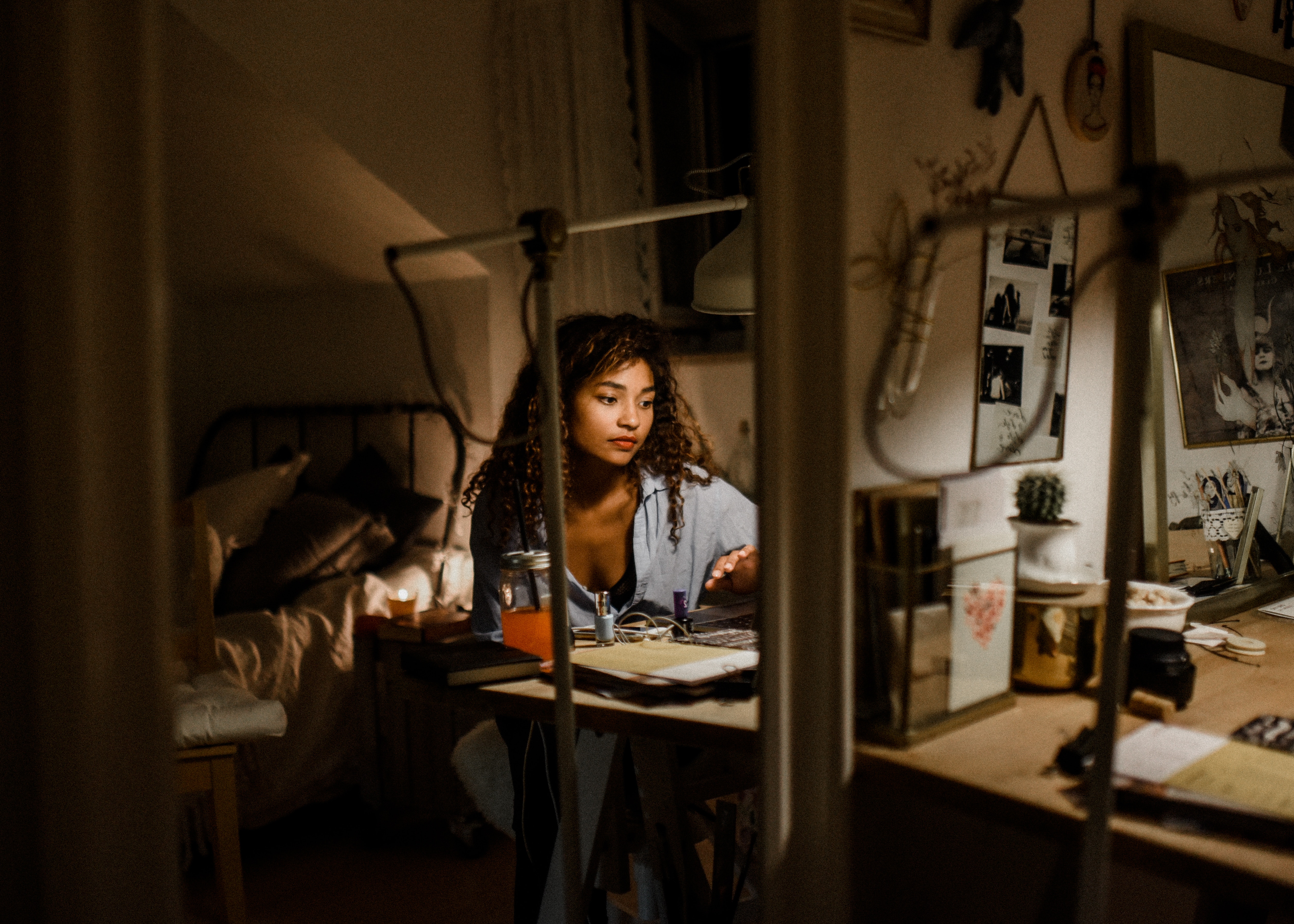Woman working at a desk in a dimly lit bedroom HD Wallpaper