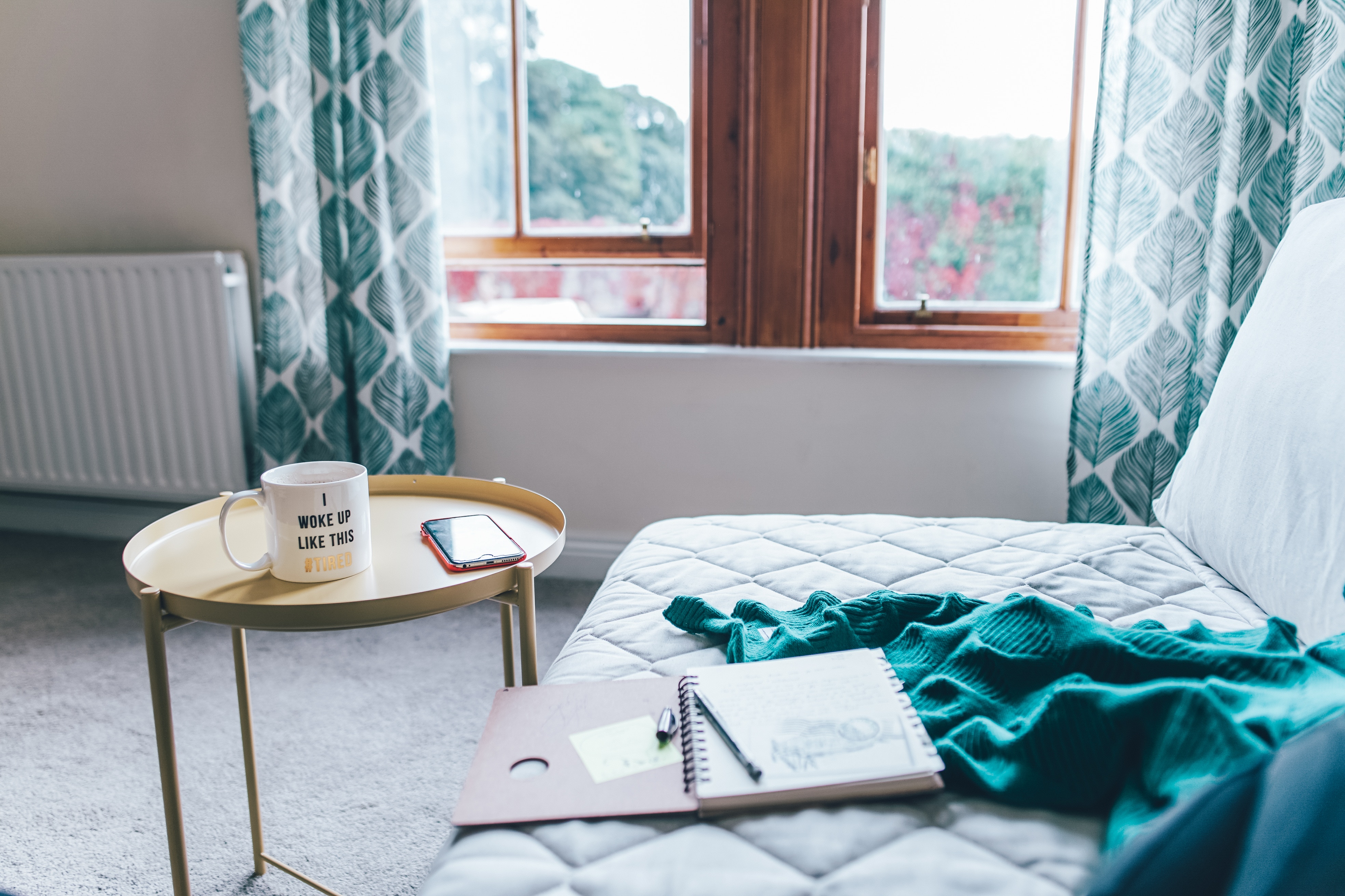 Mug, phone, and notebook on a table next to a couch HD Wallpaper