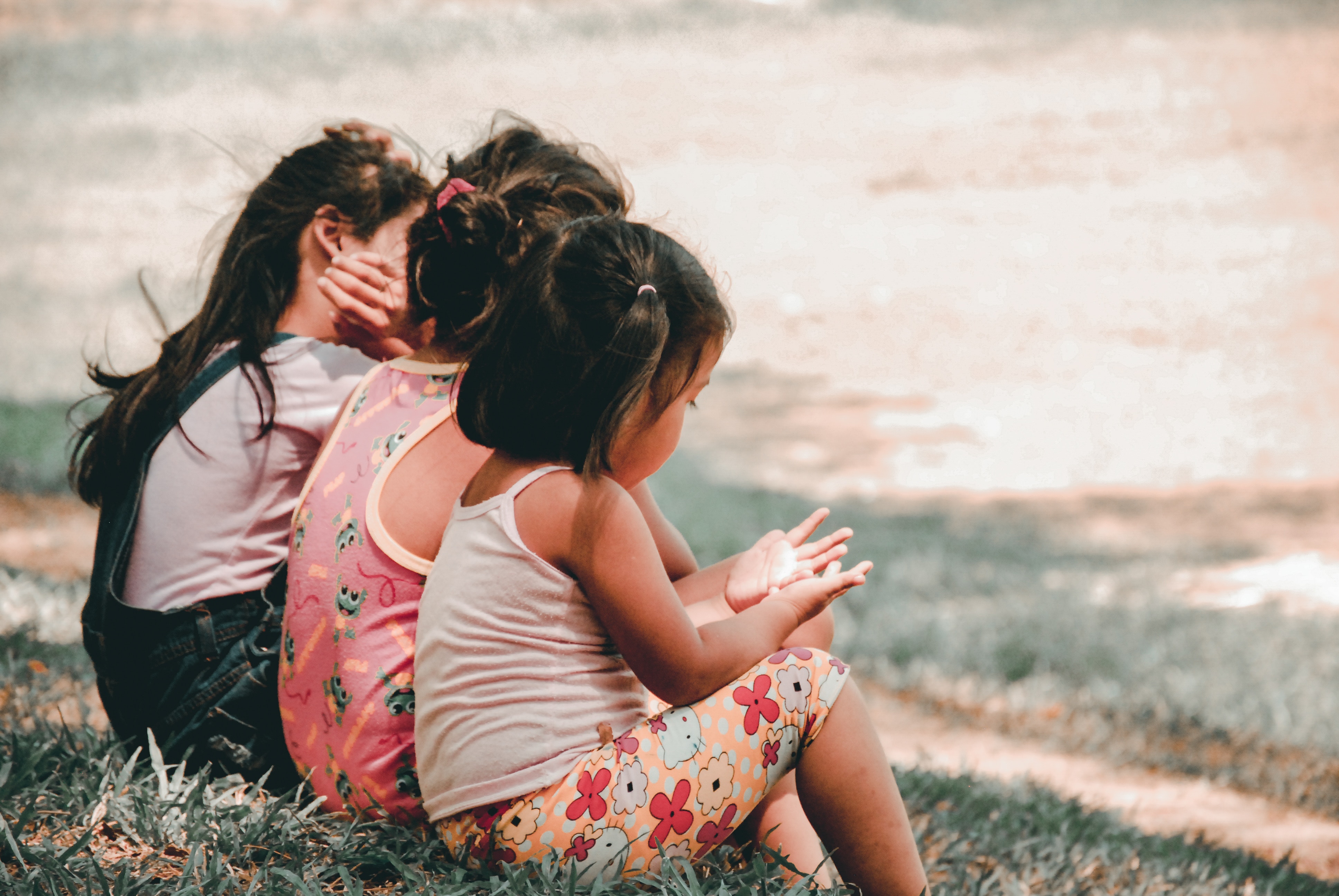 Three girls sitting on grass in a park HD Wallpaper