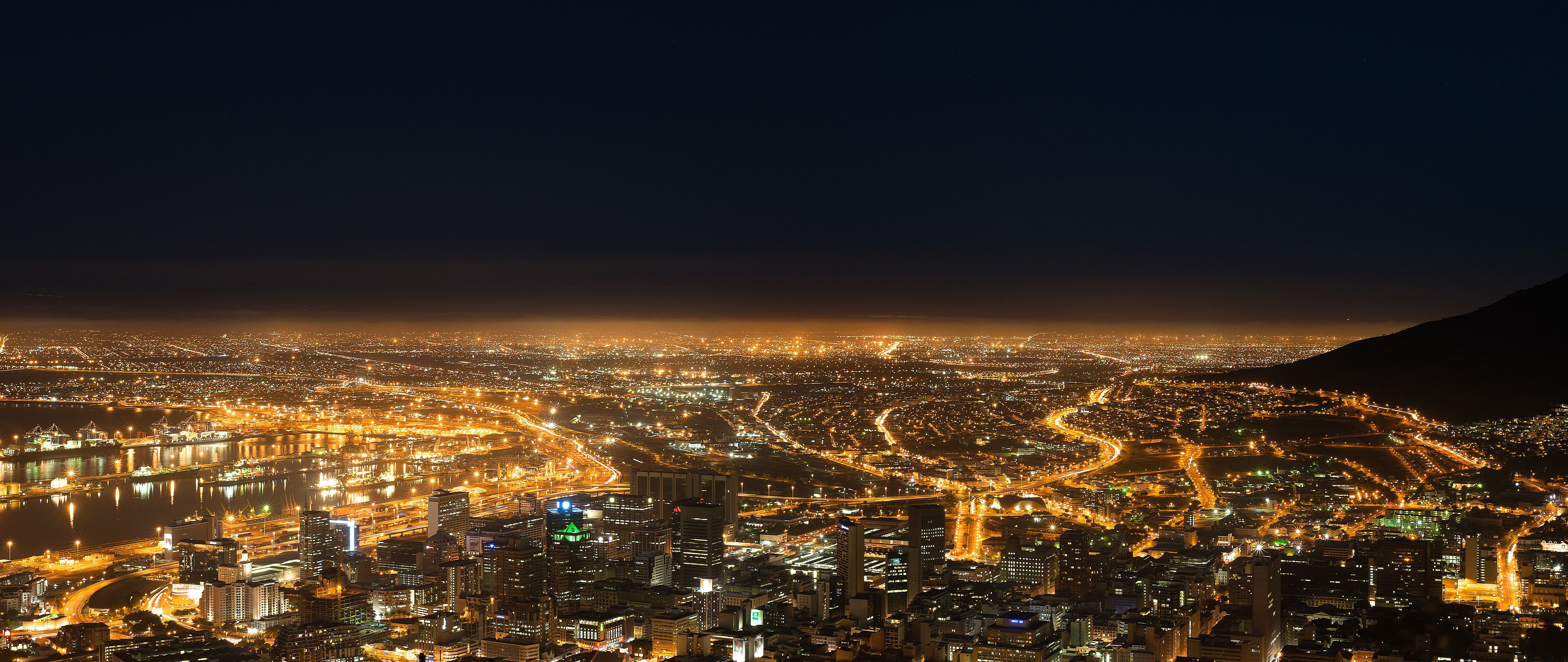 Cityscape at night with mountain silhouette HD Wallpaper
