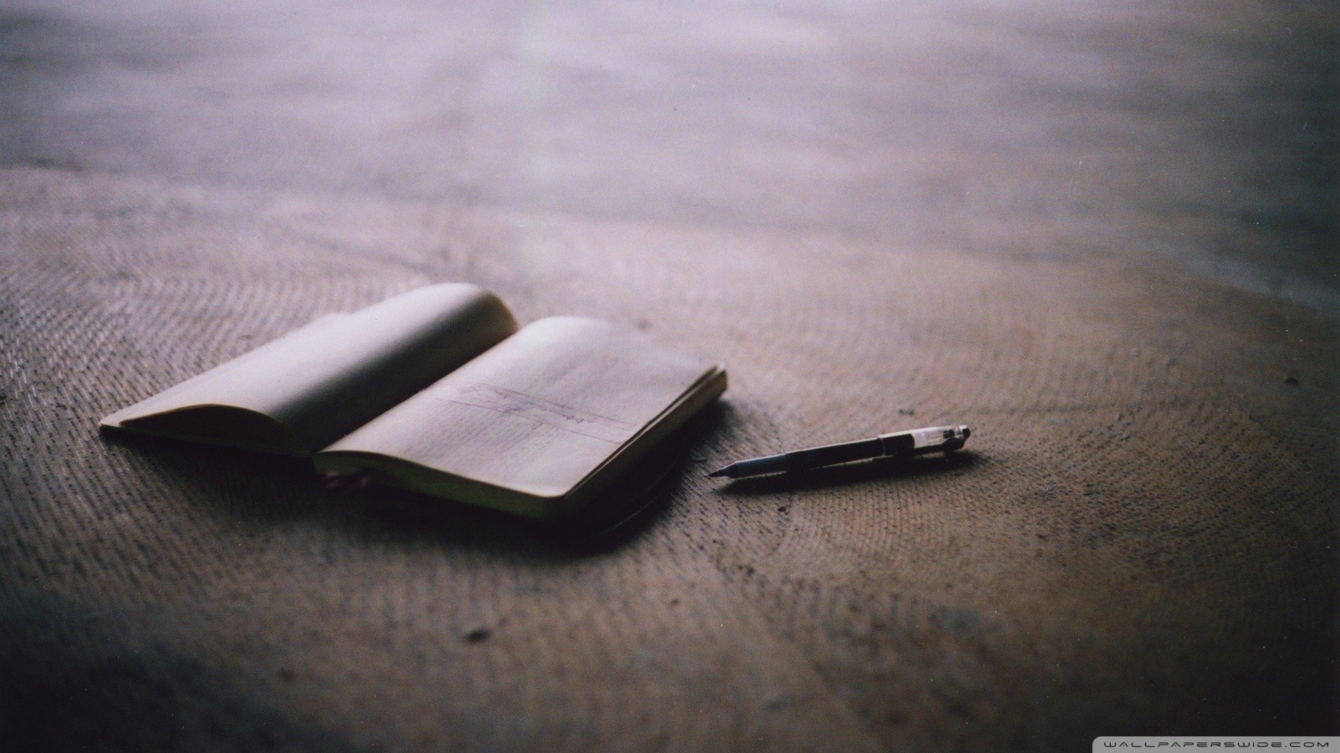 Open notebook and pen on a textured surface HD Wallpaper