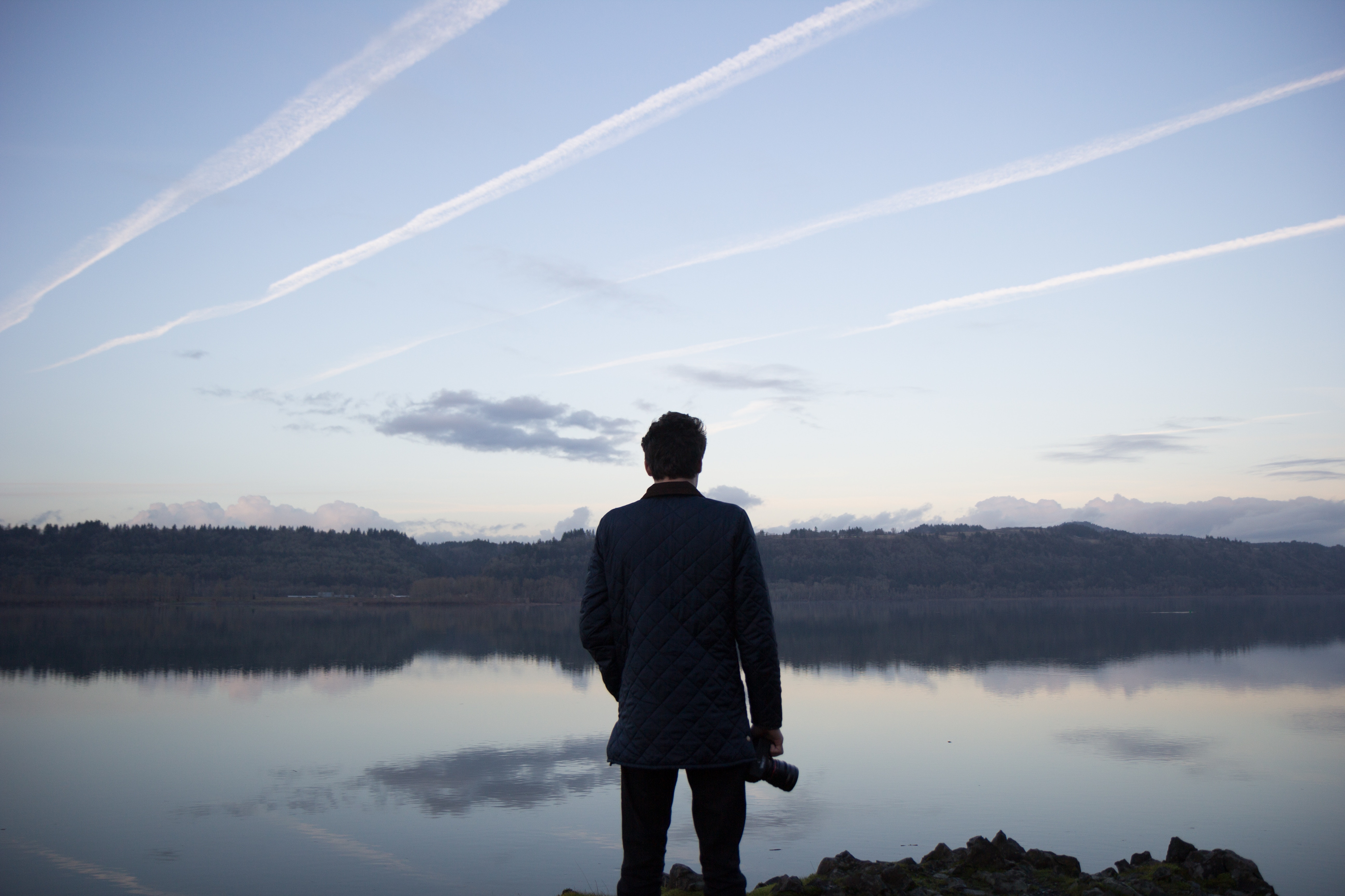 Man with camera looking at lake and sky HD Wallpaper