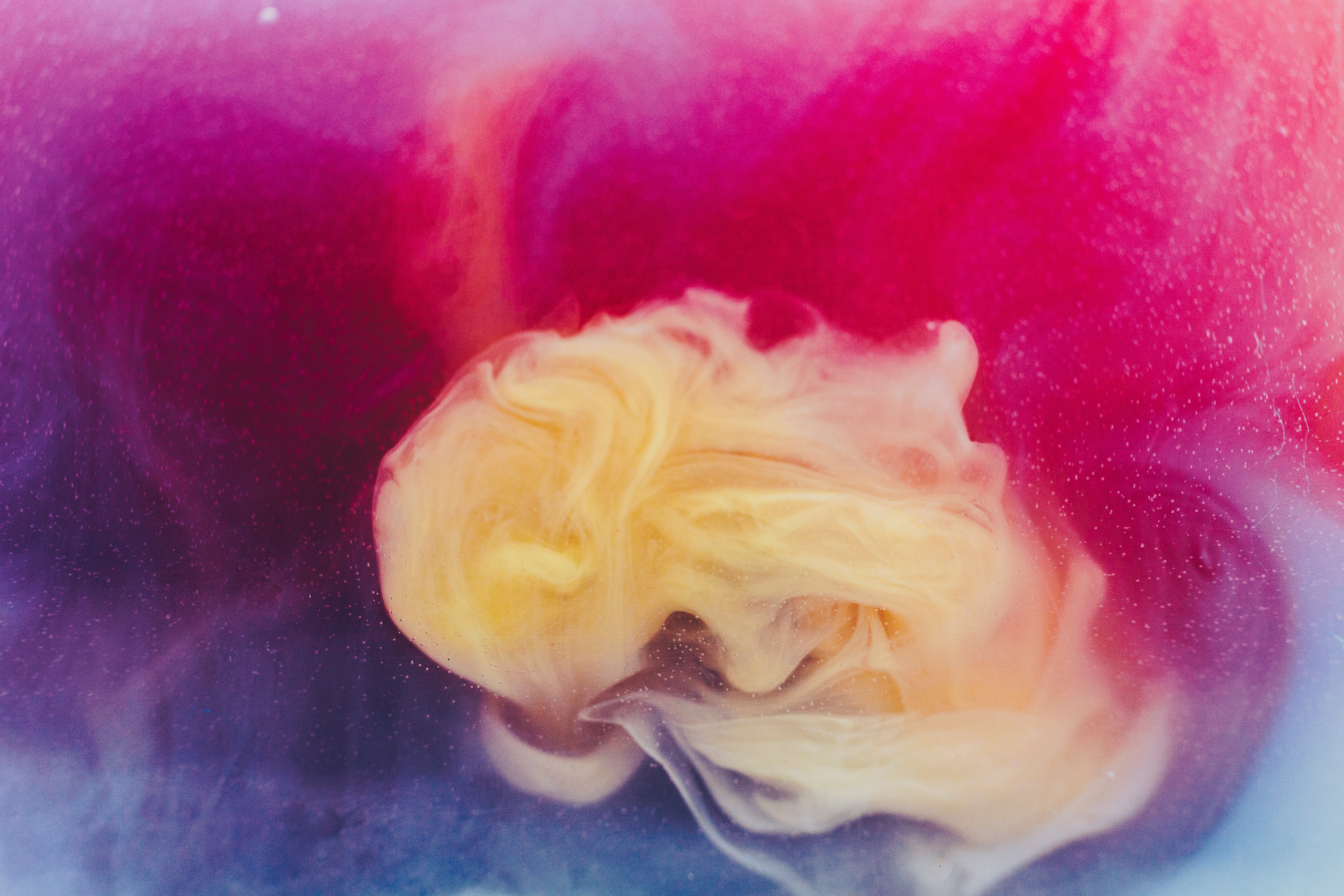 Abstract swirls of pink, yellow, and blue ink in water HD Wallpaper