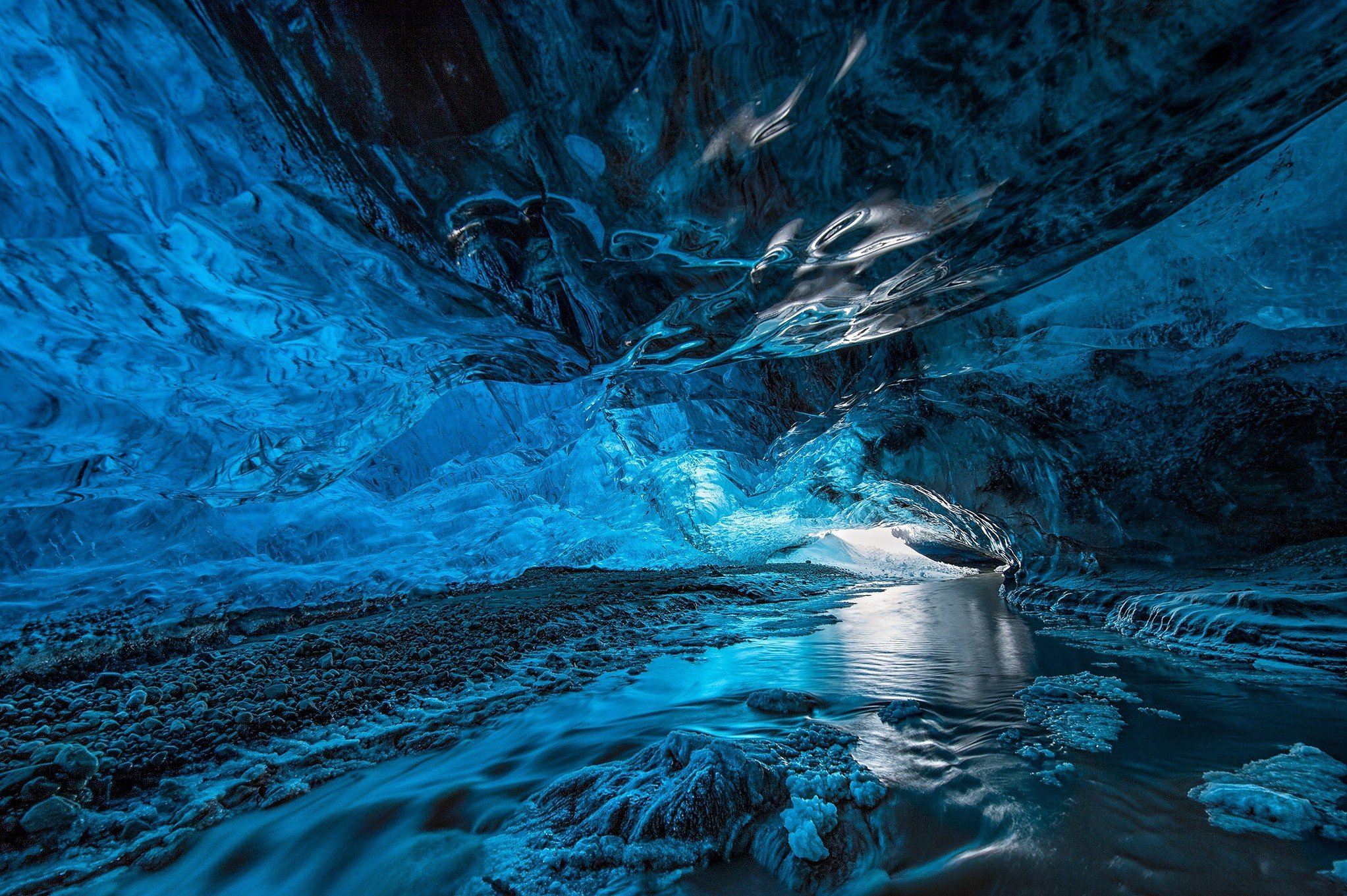 Inside a blue ice cave with flowing water HD Wallpaper