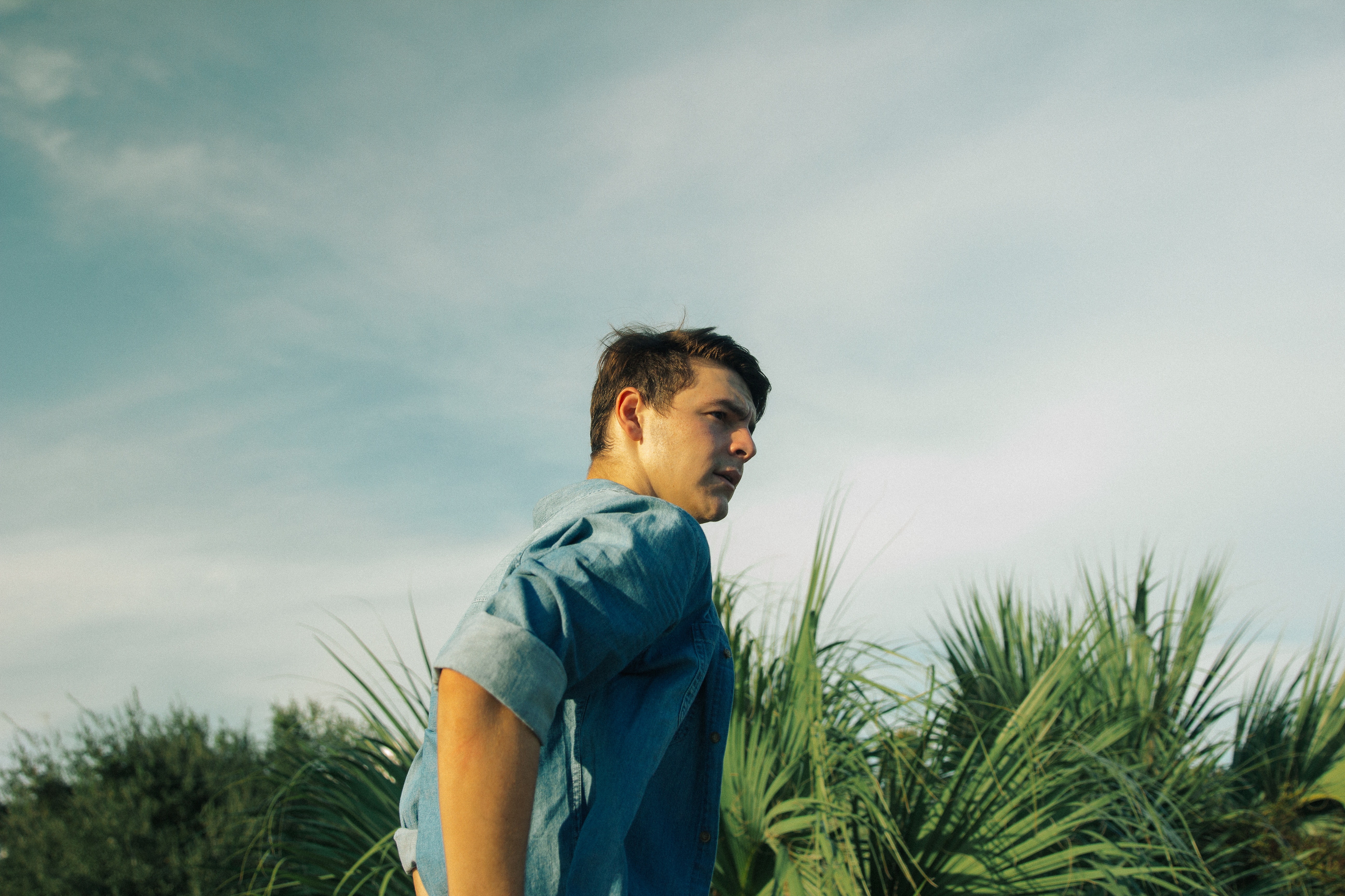 Man in blue shirt looking away outdoors HD Wallpaper