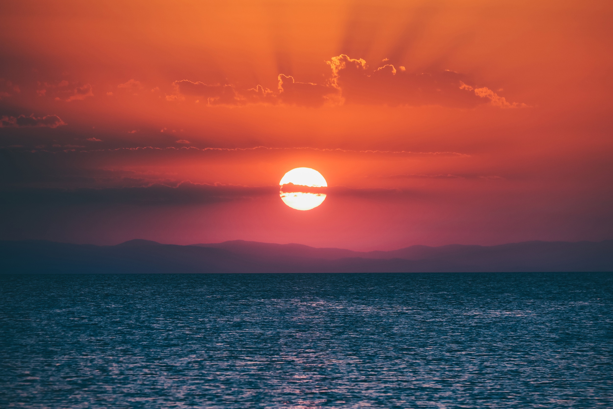 Sunset over the ocean with mountains HD Wallpaper
