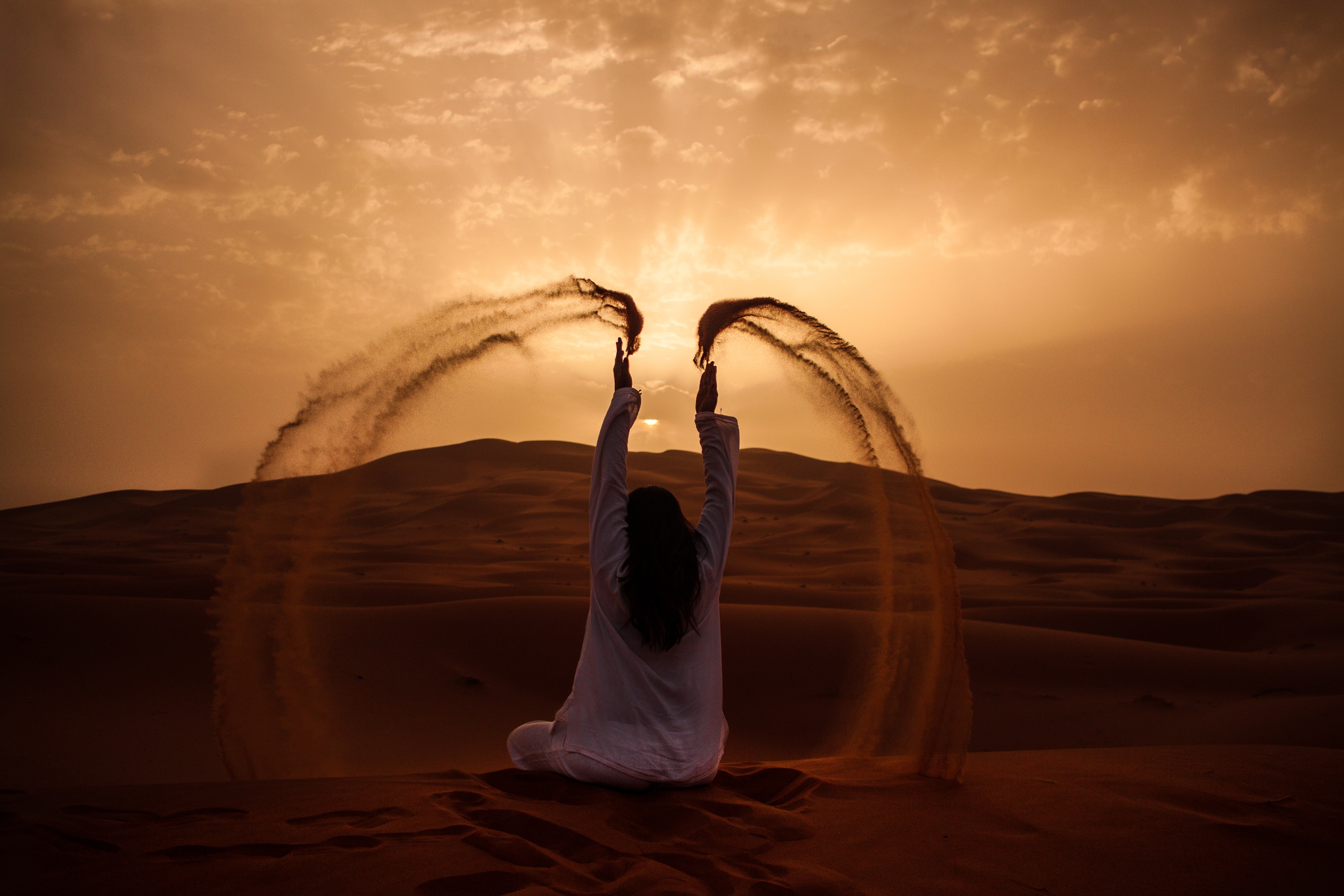 Woman throwing sand in the desert at sunset HD Wallpaper