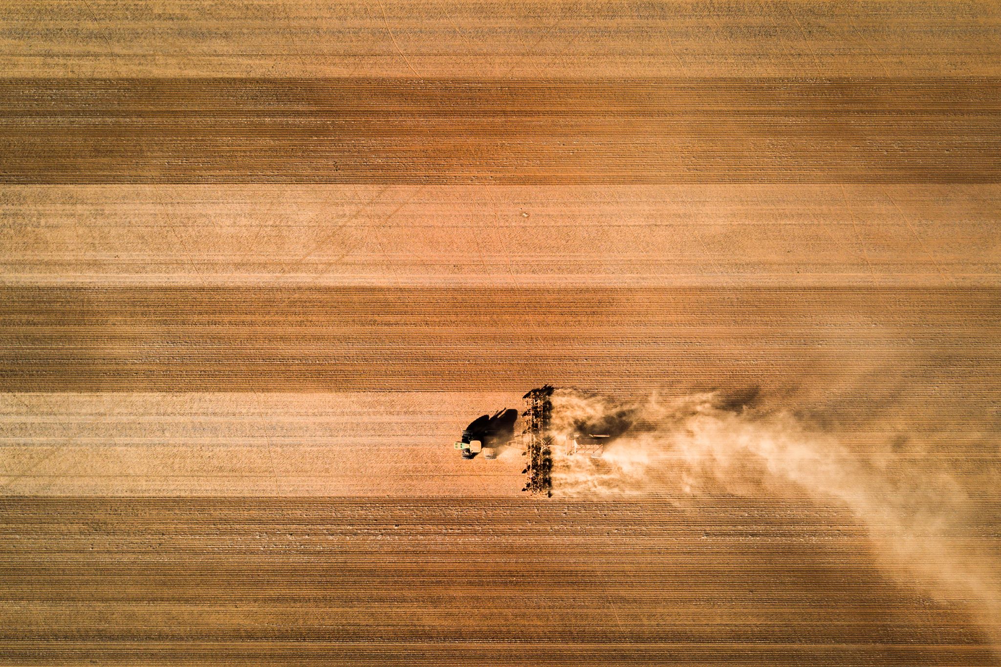 Tractor plowing a field, aerial view HD Wallpaper