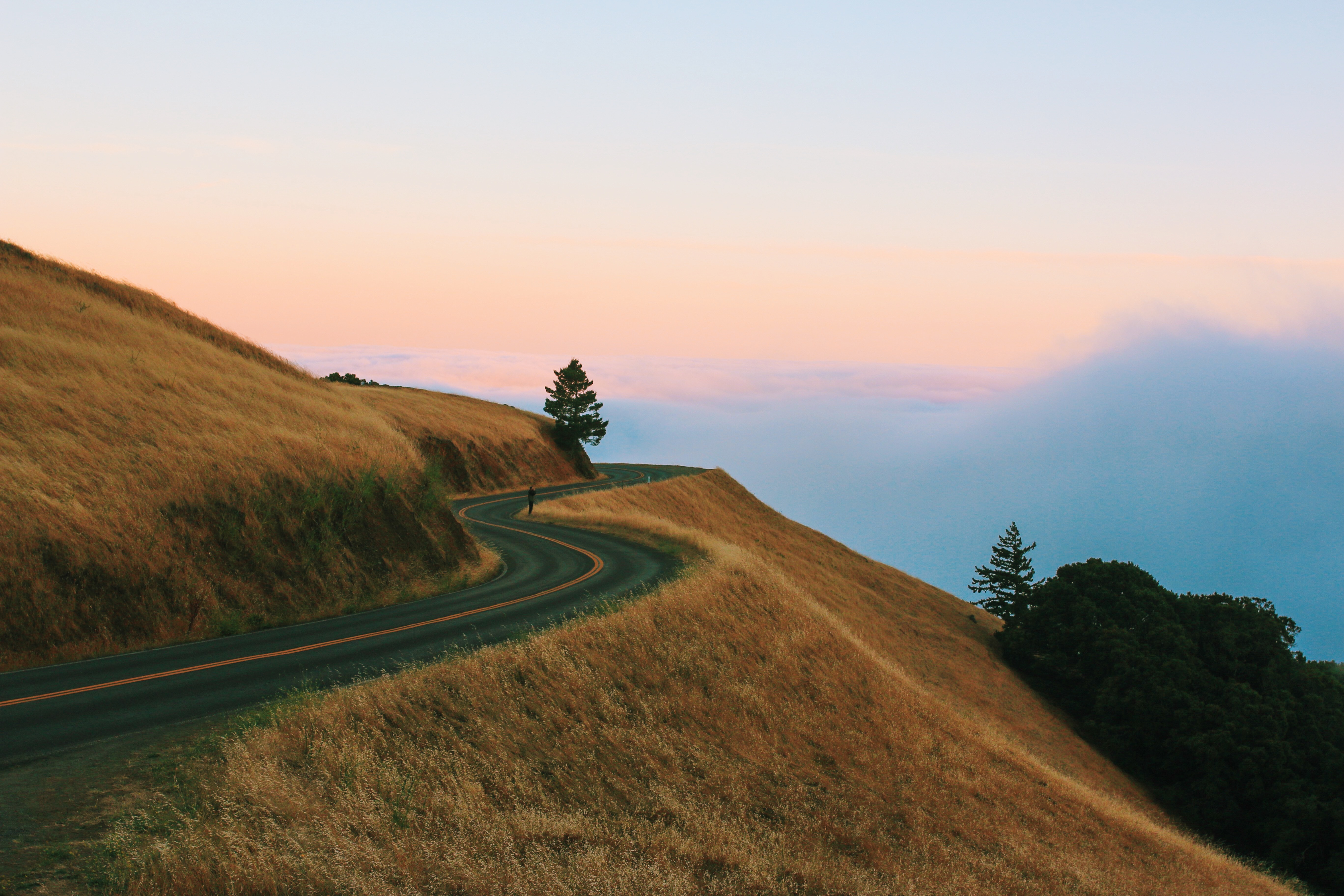 Winding mountain road at sunset with clouds HD Wallpaper