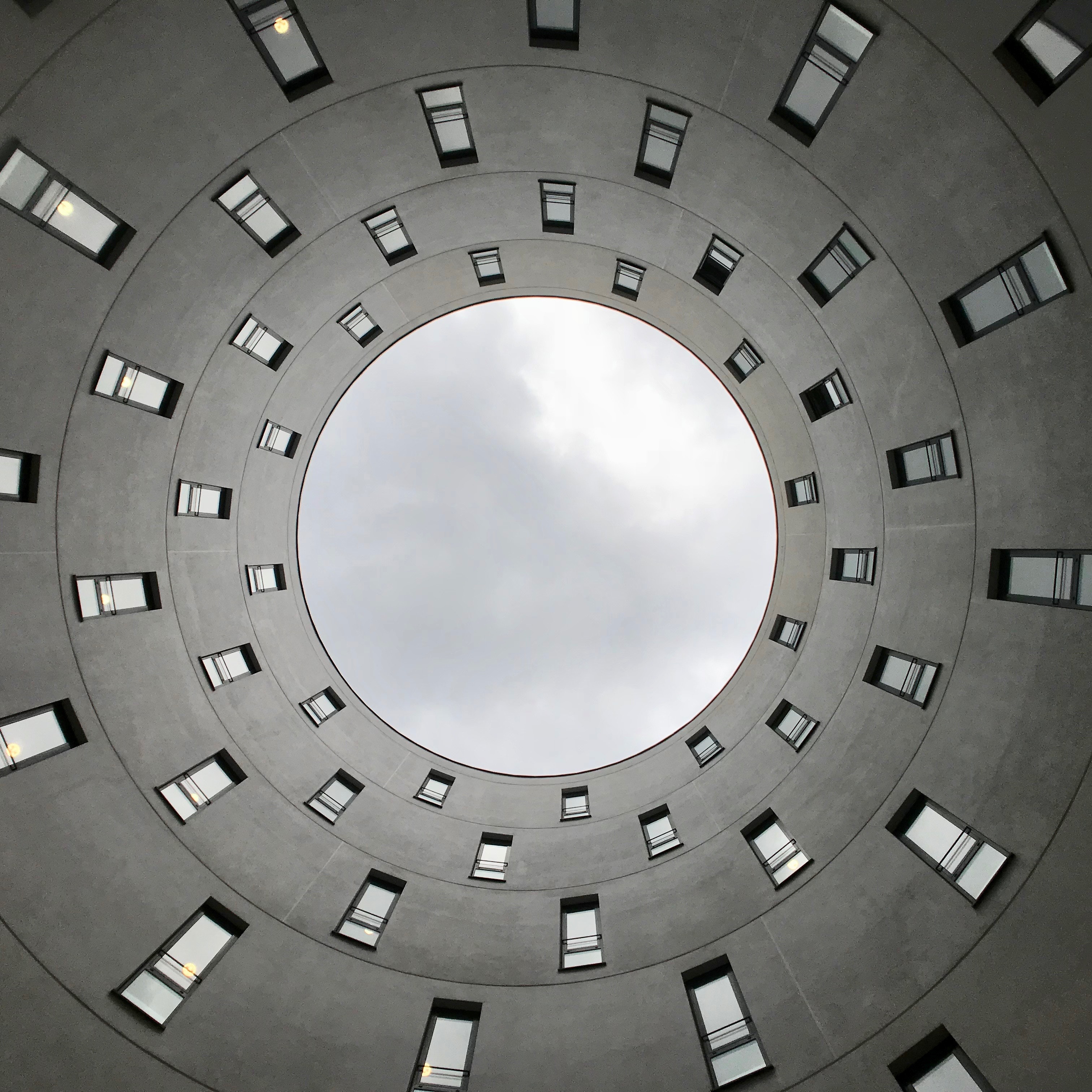 Concentric circles of windows in a building looking up at the sky HD Wallpaper