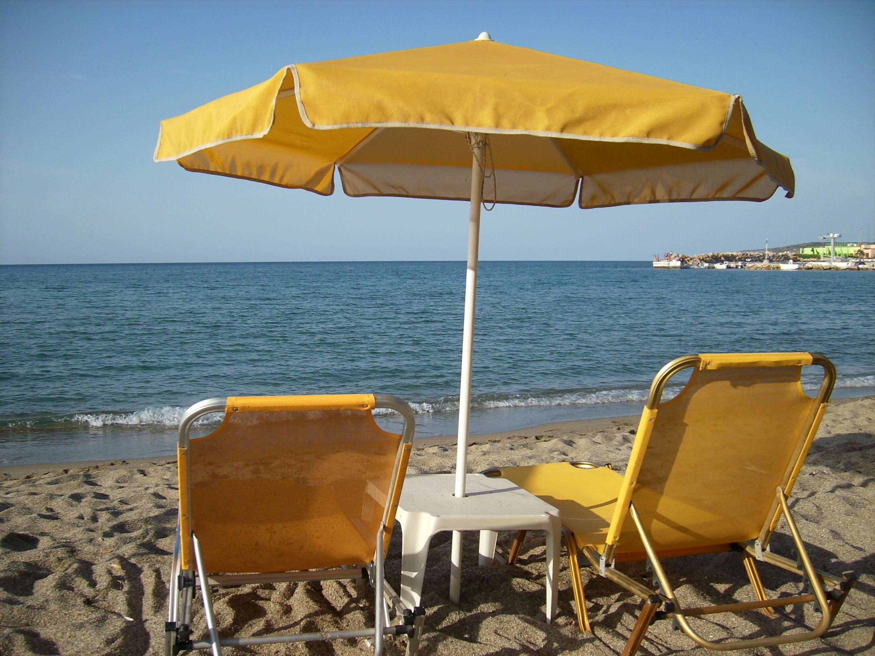 Beach chairs and umbrella by the sea HD Wallpaper