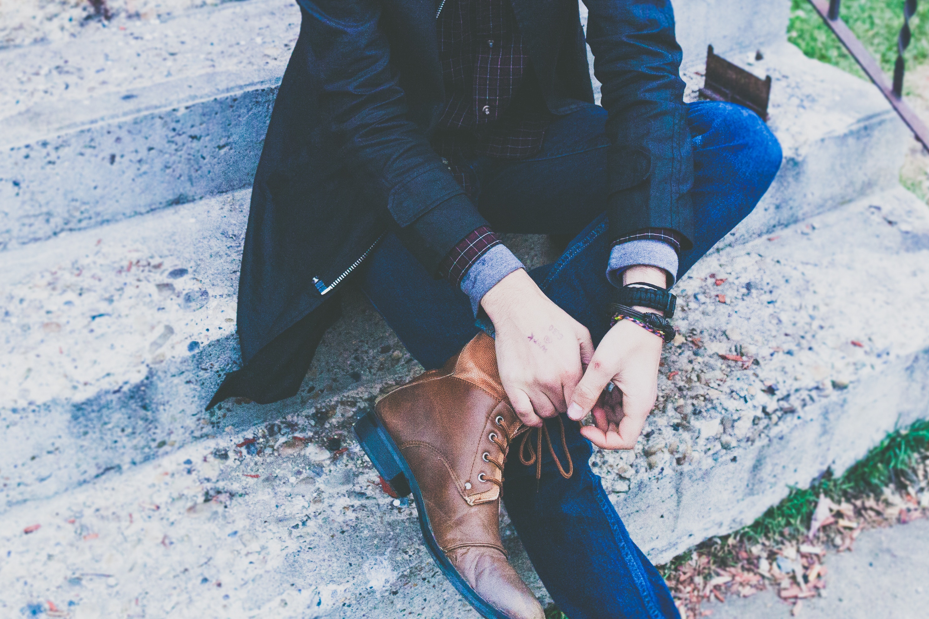 Man in jacket and jeans sitting on concrete steps HD Wallpaper