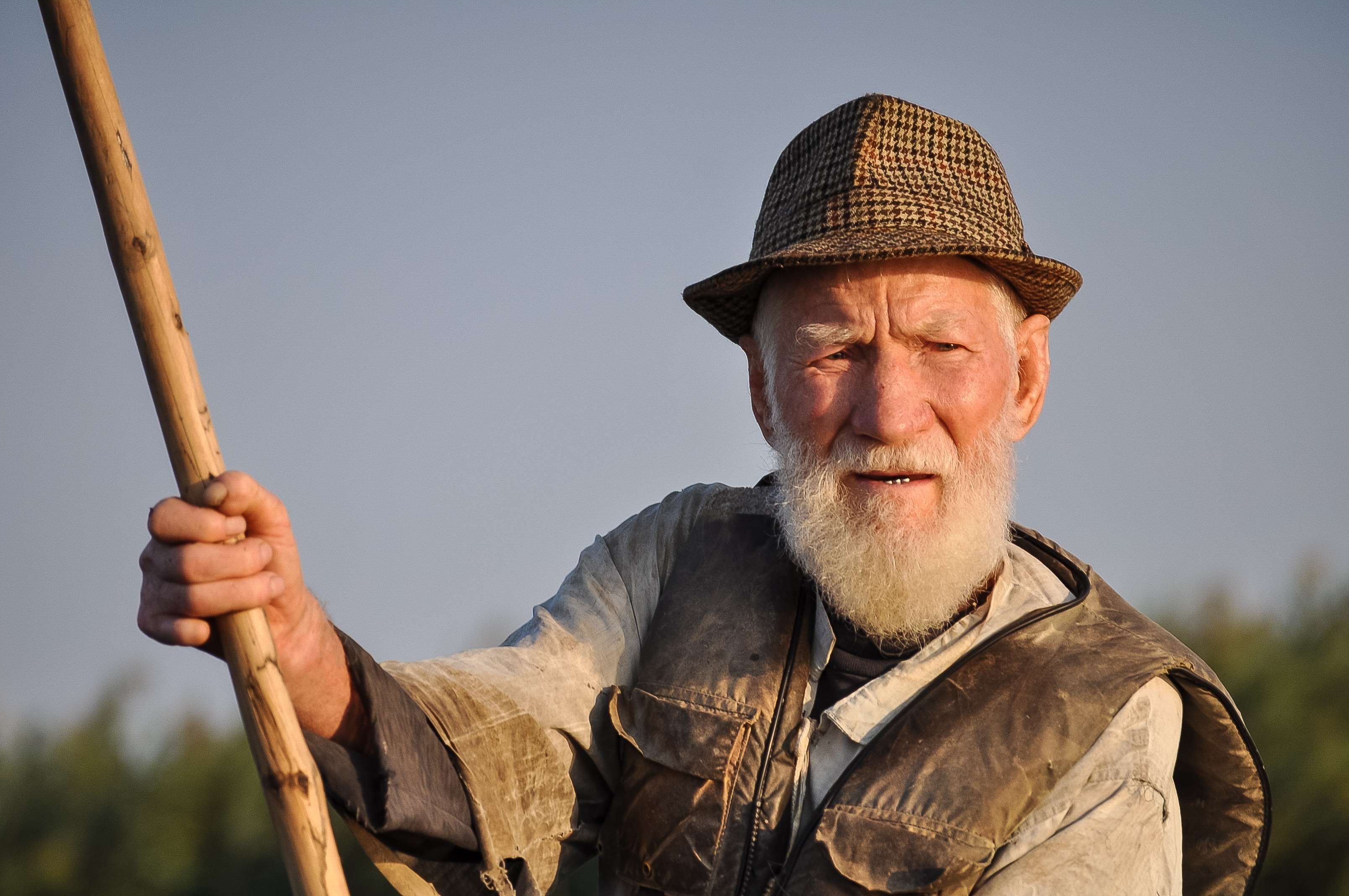 Elderly man with white beard holding a wooden stick HD Wallpaper