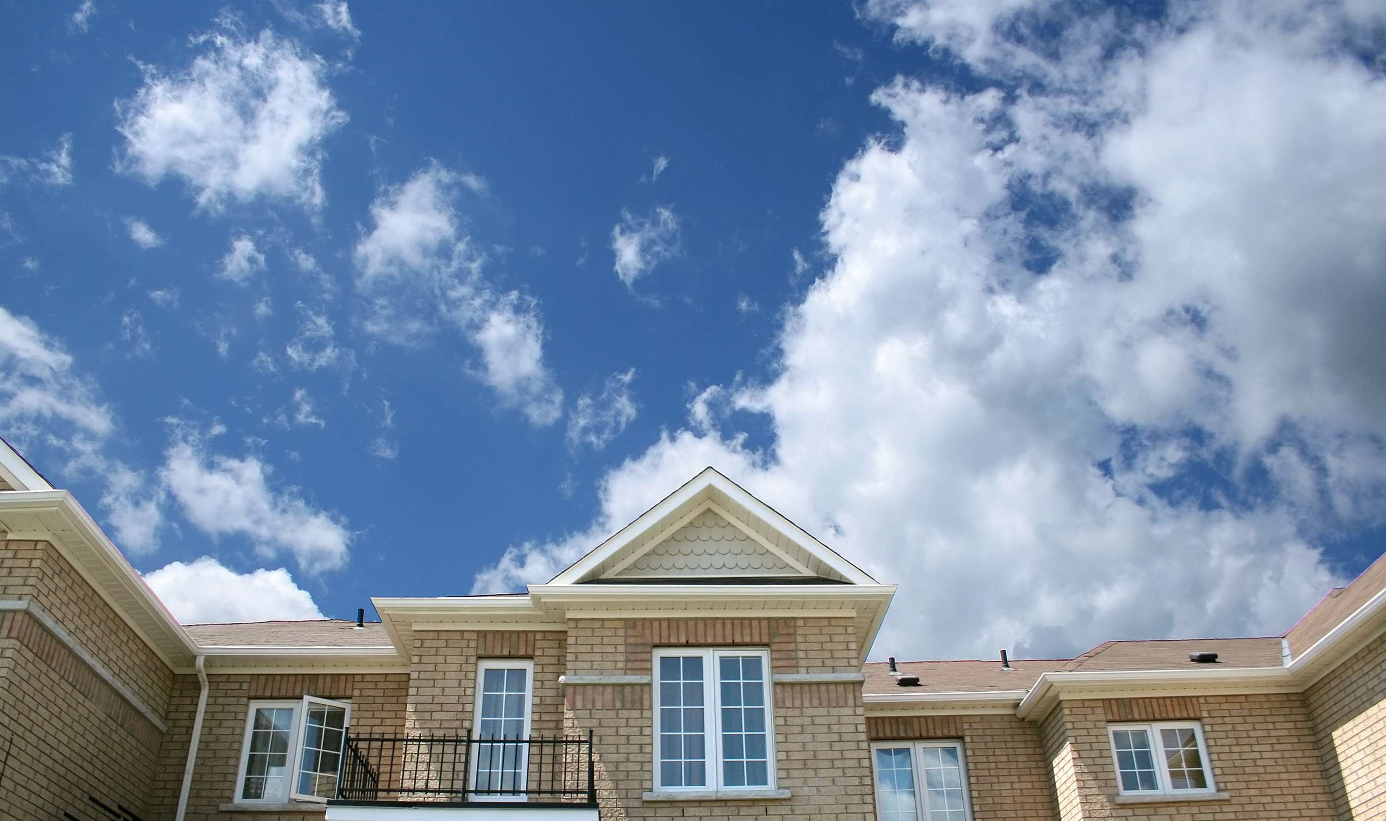 Brick building with white trim and blue sky with clouds HD Wallpaper