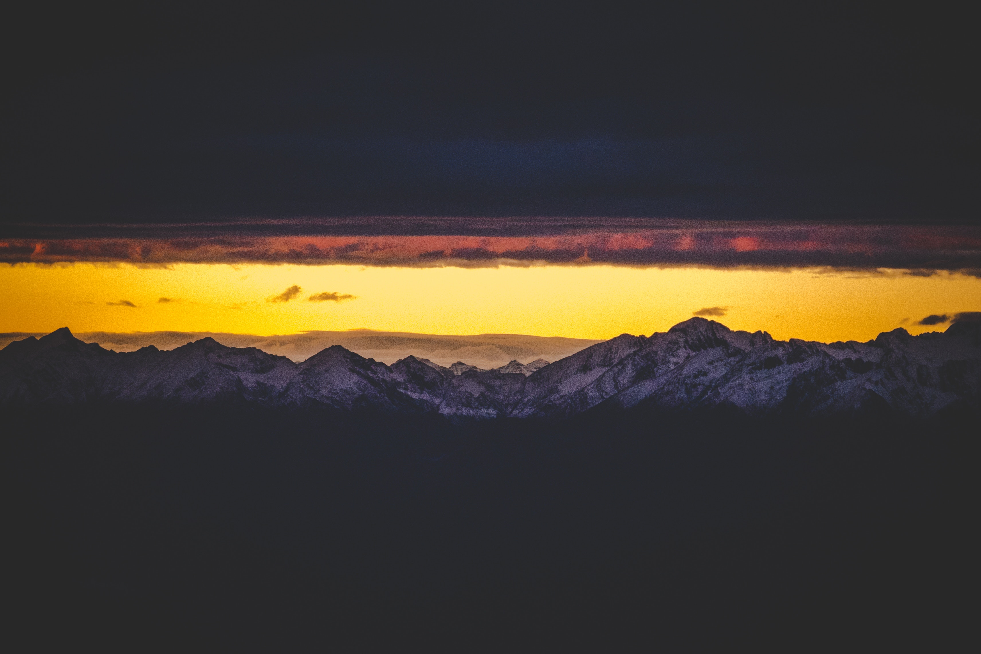 Dark Mountain Range Under a Yellow Sunset Sky HD Wallpaper