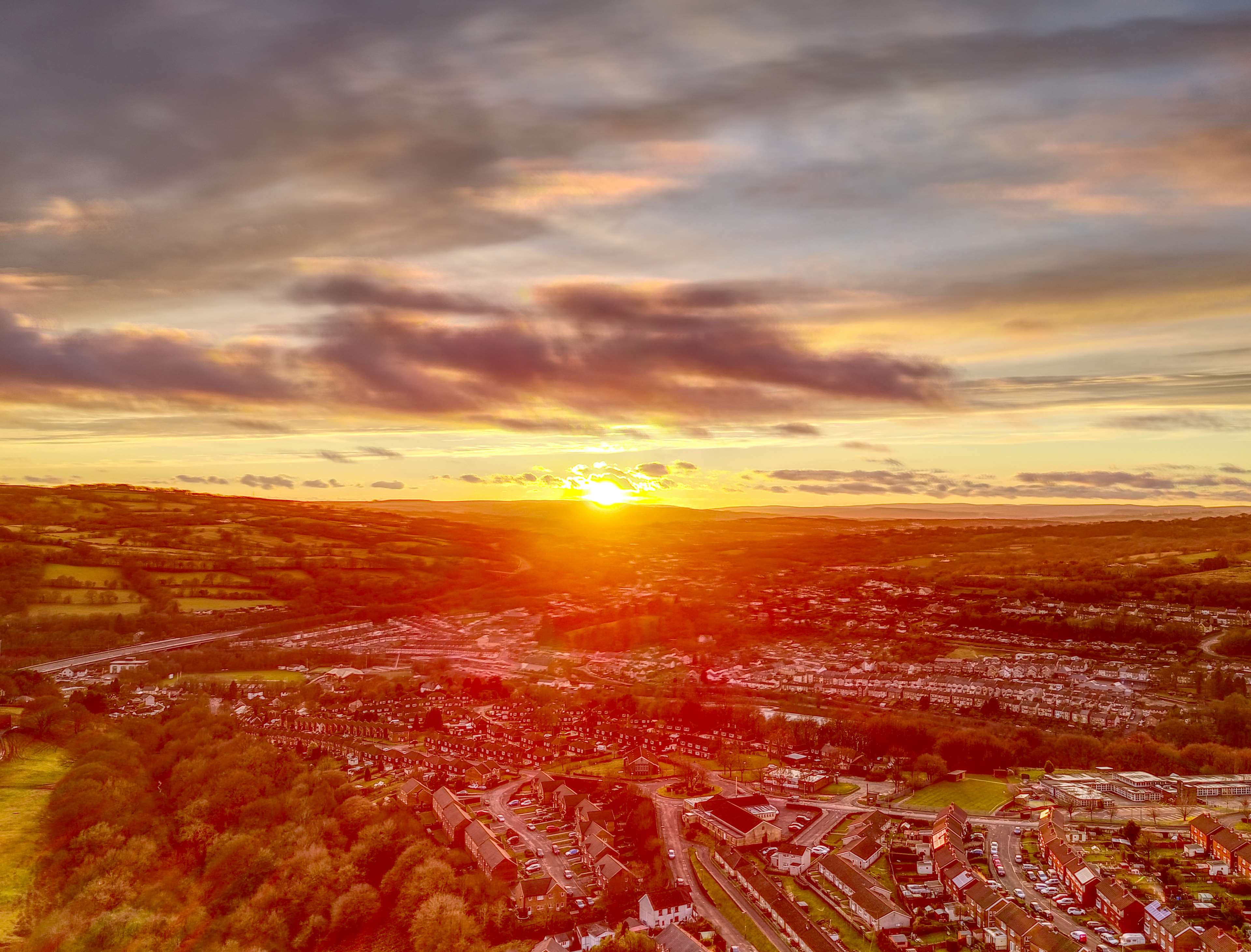 Sunset over rolling hills and a town HD Wallpaper