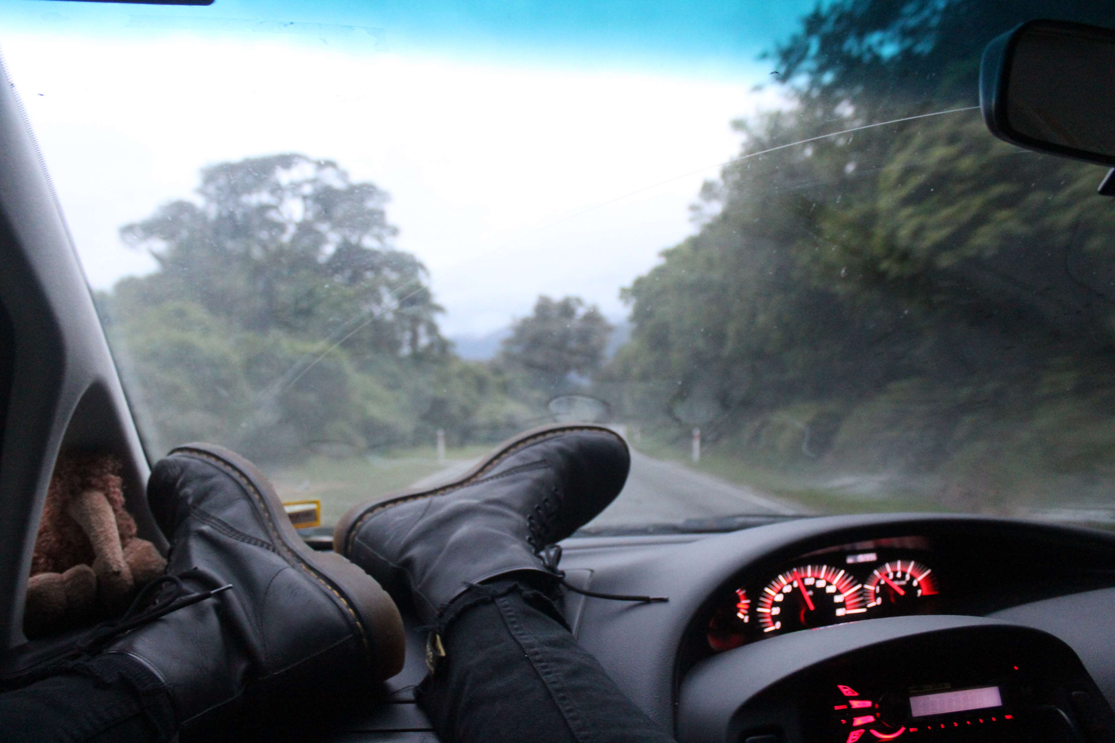 Feet on dashboard during a road trip through a forest HD Wallpaper