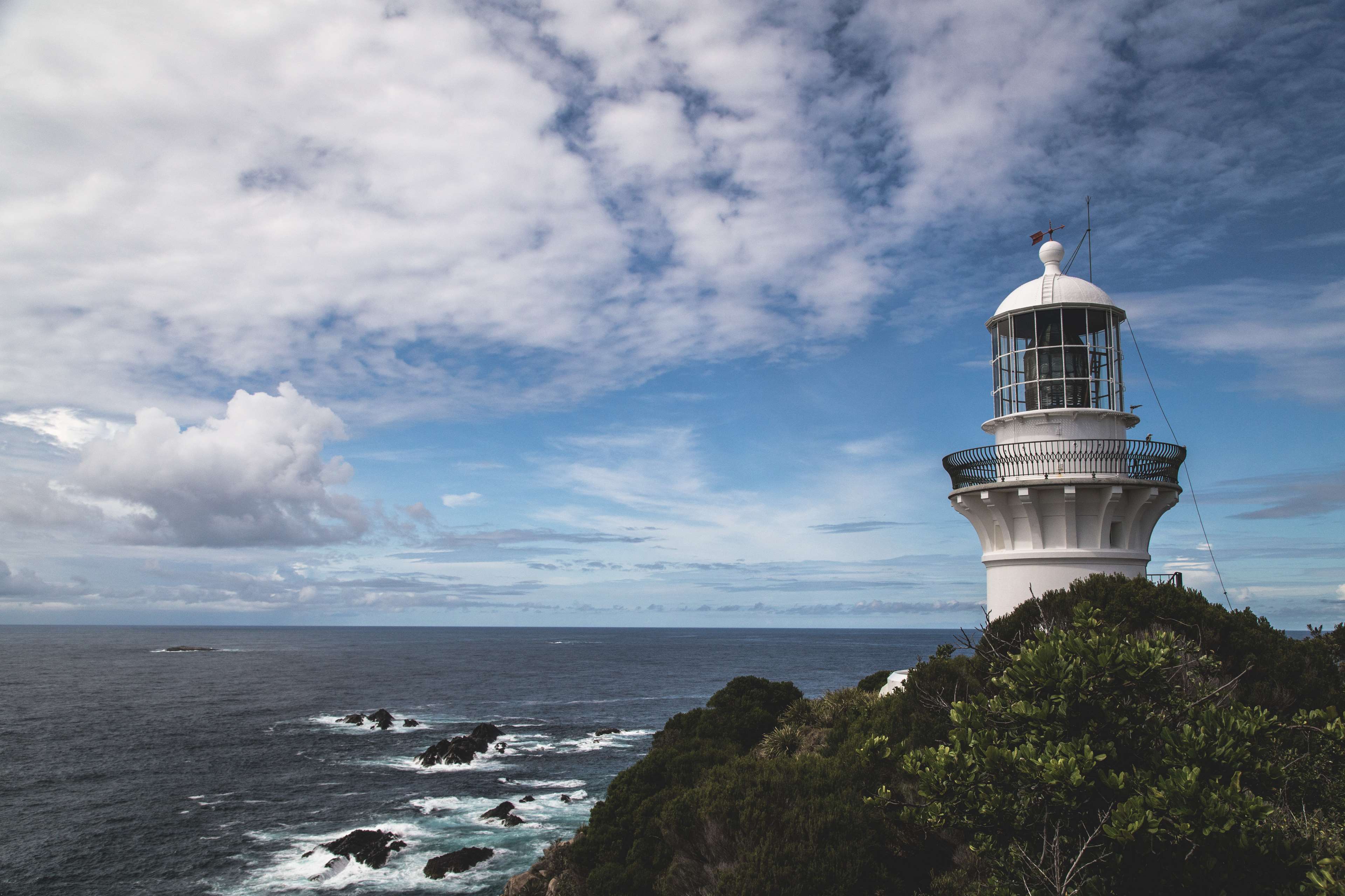 White lighthouse on a cliff overlooking the ocean HD Wallpaper