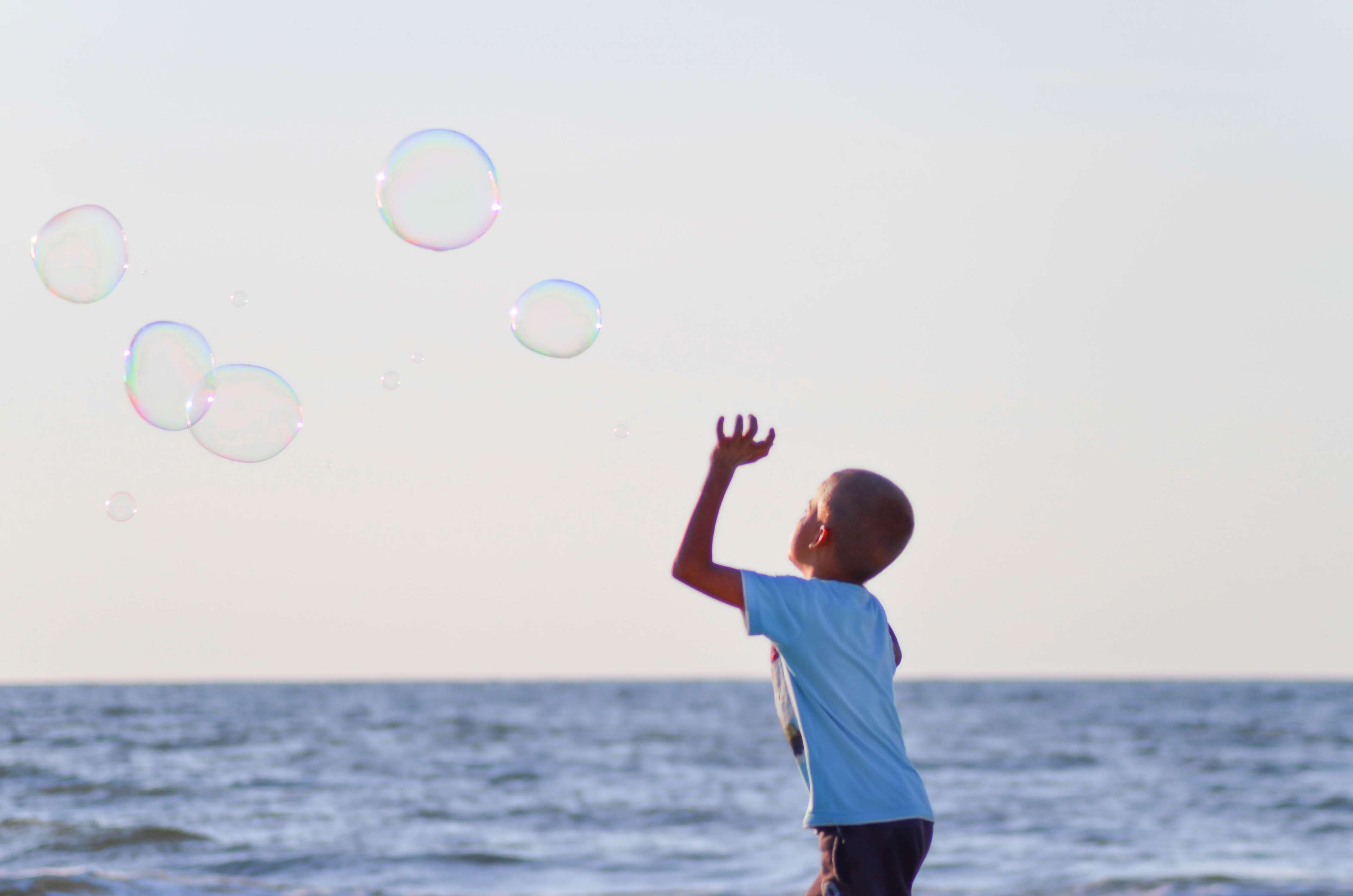 Boy playing with bubbles at the beach HD Wallpaper
