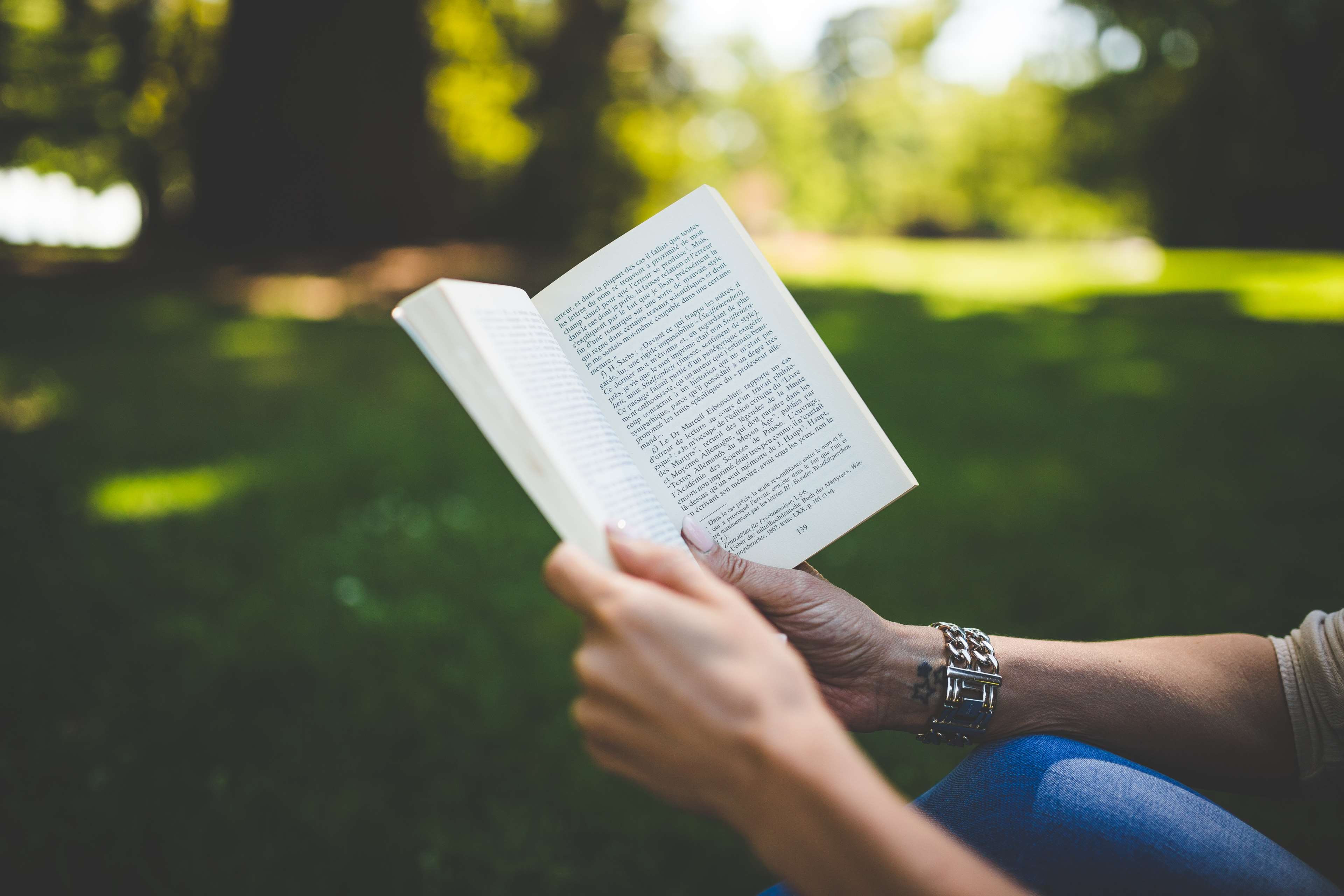 Person reading a book in a park HD Wallpaper