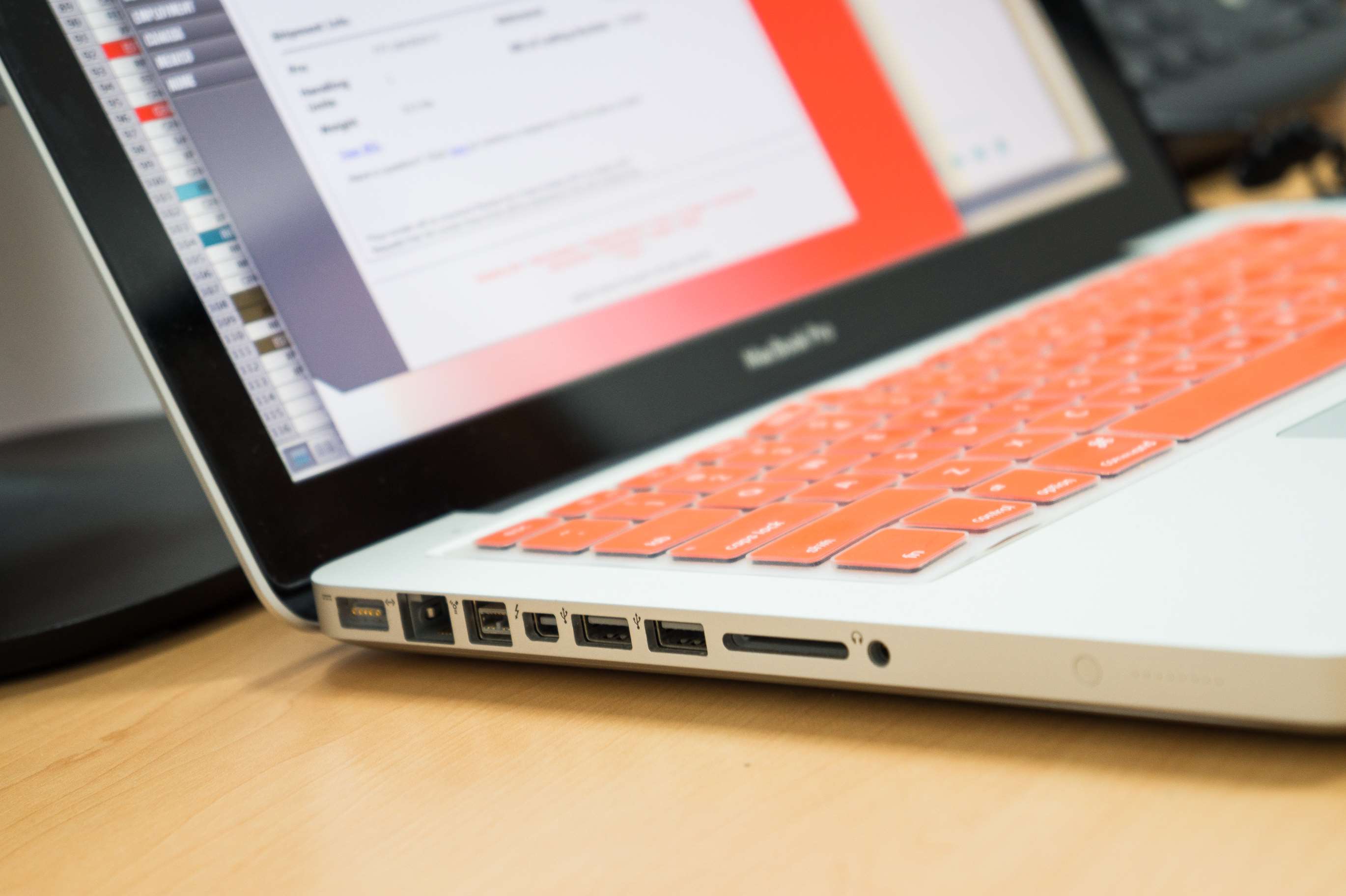 MacBook Pro with orange keyboard on a desk HD Wallpaper