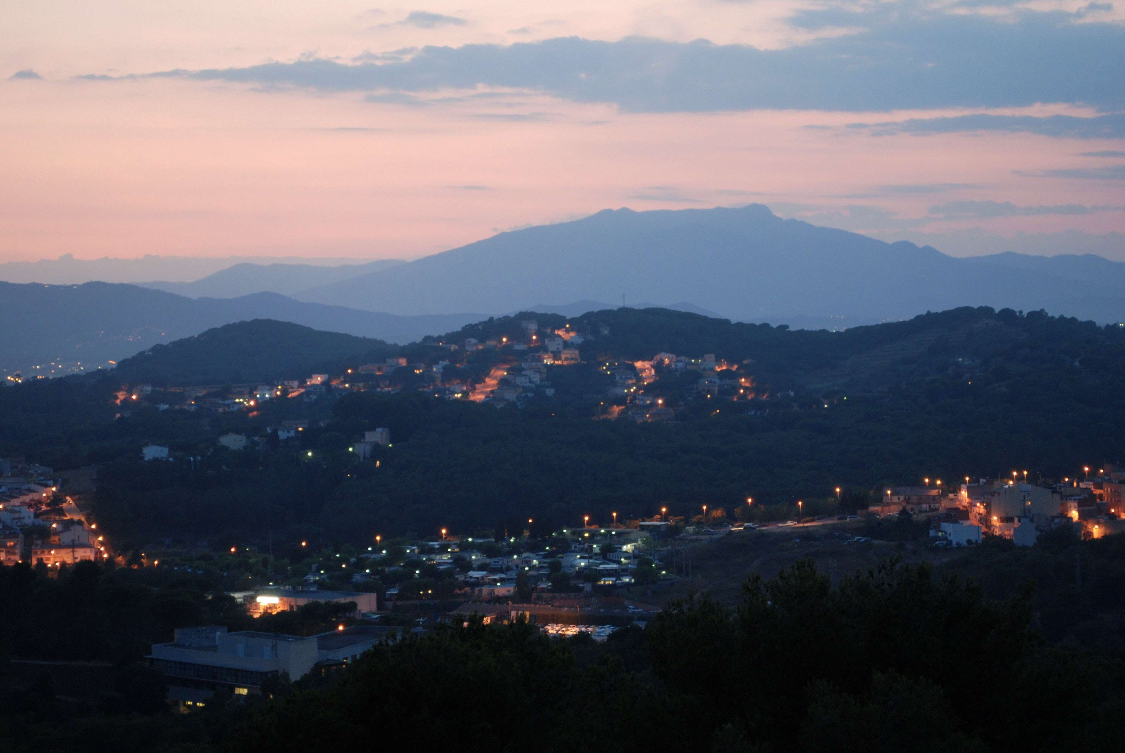 Town lights on hills at dusk with mountains in background HD Wallpaper